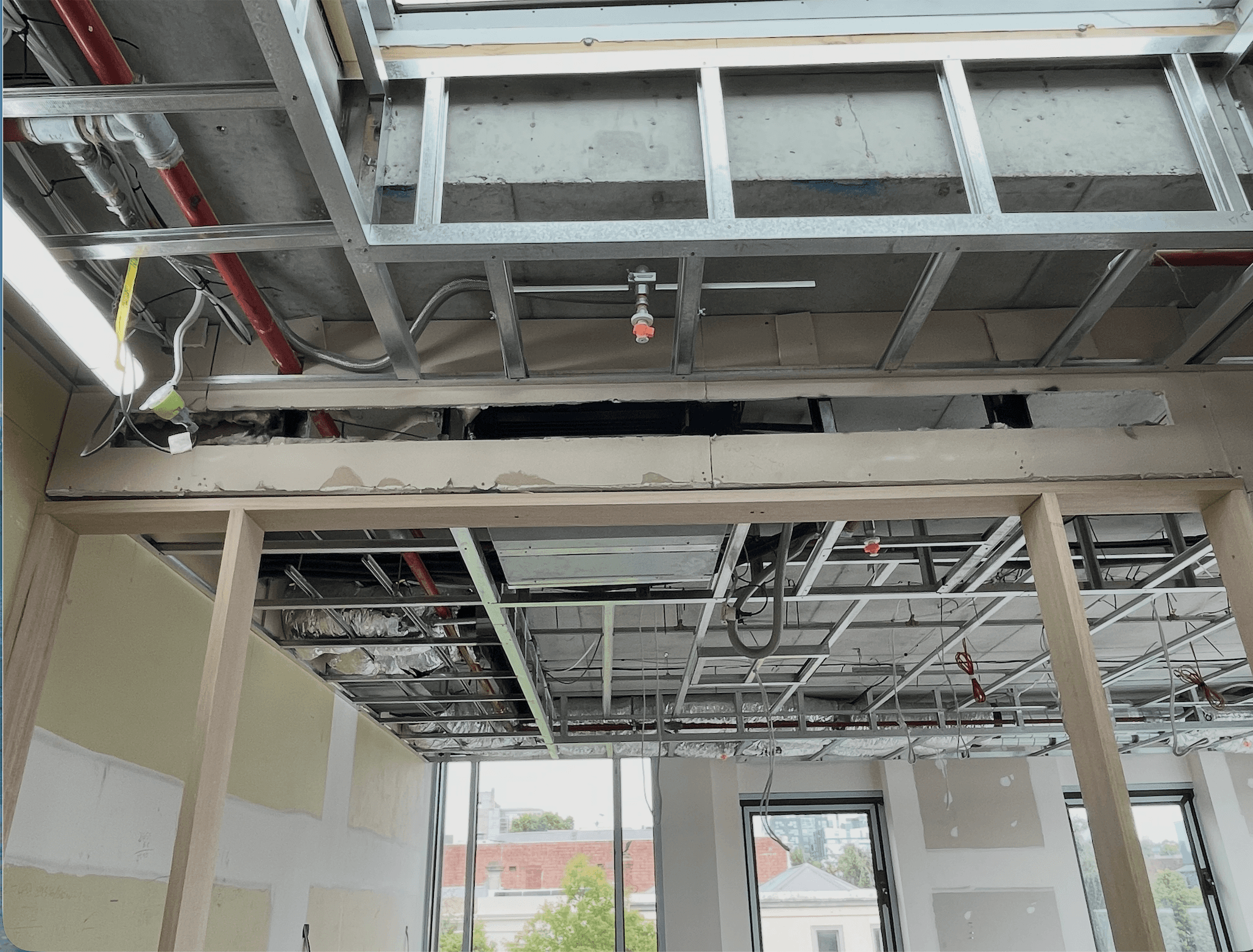 Modern glass and wood cabin with a cozy outdoor deck featuring wicker furniture, surrounded by lush green trees and a serene forest setting.