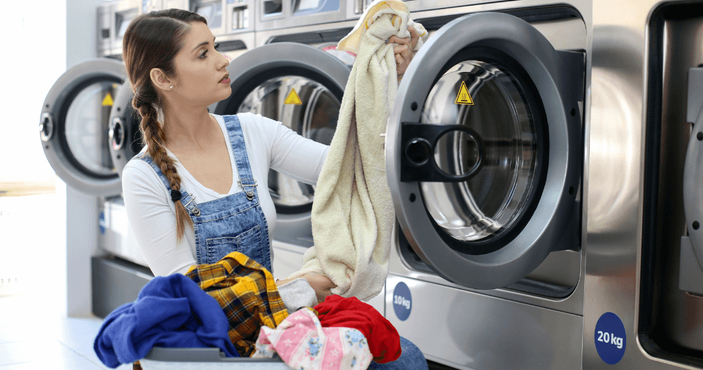 Woman doing laundry at a laundromat with industrial washers