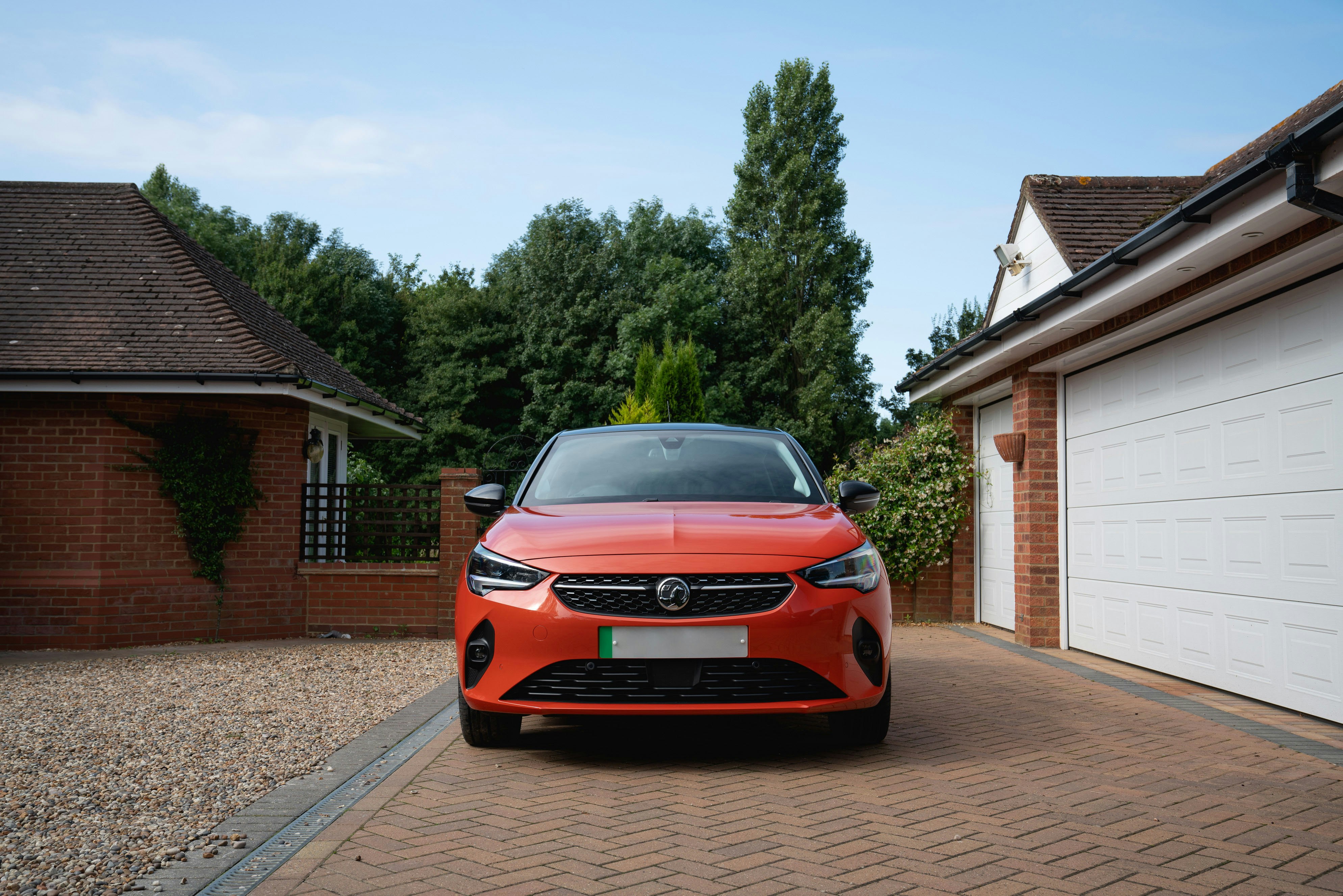 Orange car parked in driveway between garages.