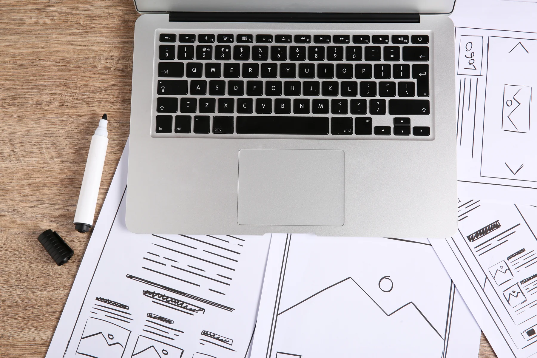 Modern Laptop and Website Wireframe Sketches on a Wooden Desk