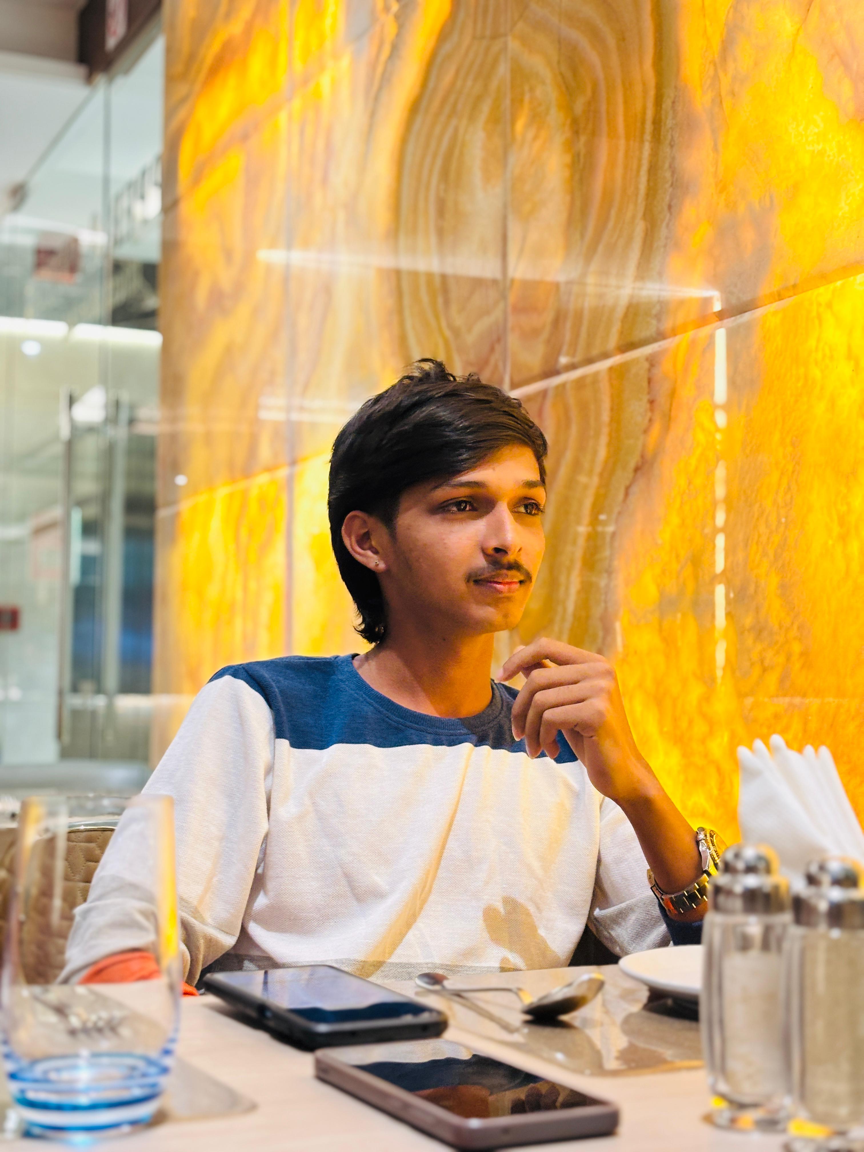 a man wearing glasses and a blazer with a lighting that casts a soft shadow on the wall behind him