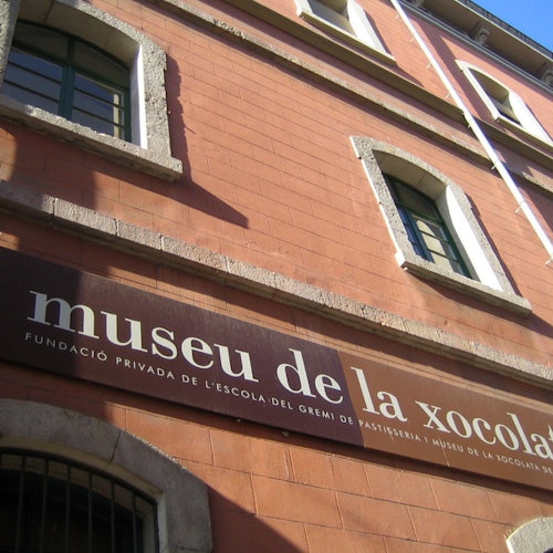 Exterior of a red brick building with arched windows, bearing a sign that reads "museu de la xocolata."
