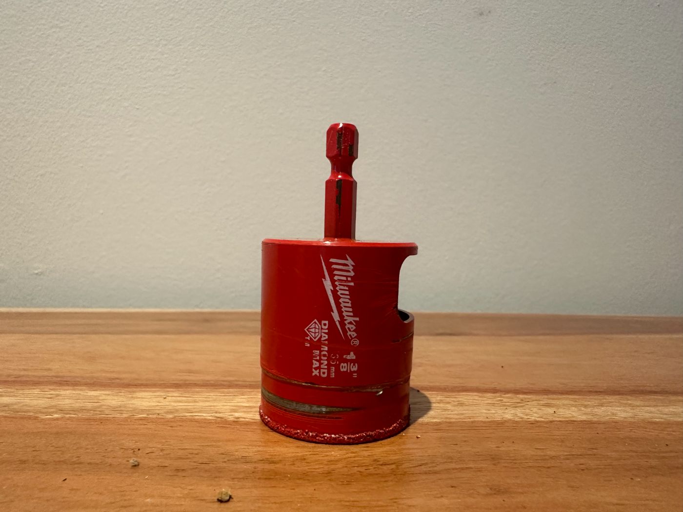 Cloche diamantée Milwaukee de 1-3/8 pouces pour perçage dans céramique, carrelage ou pierre, posée sur un plancher en bois