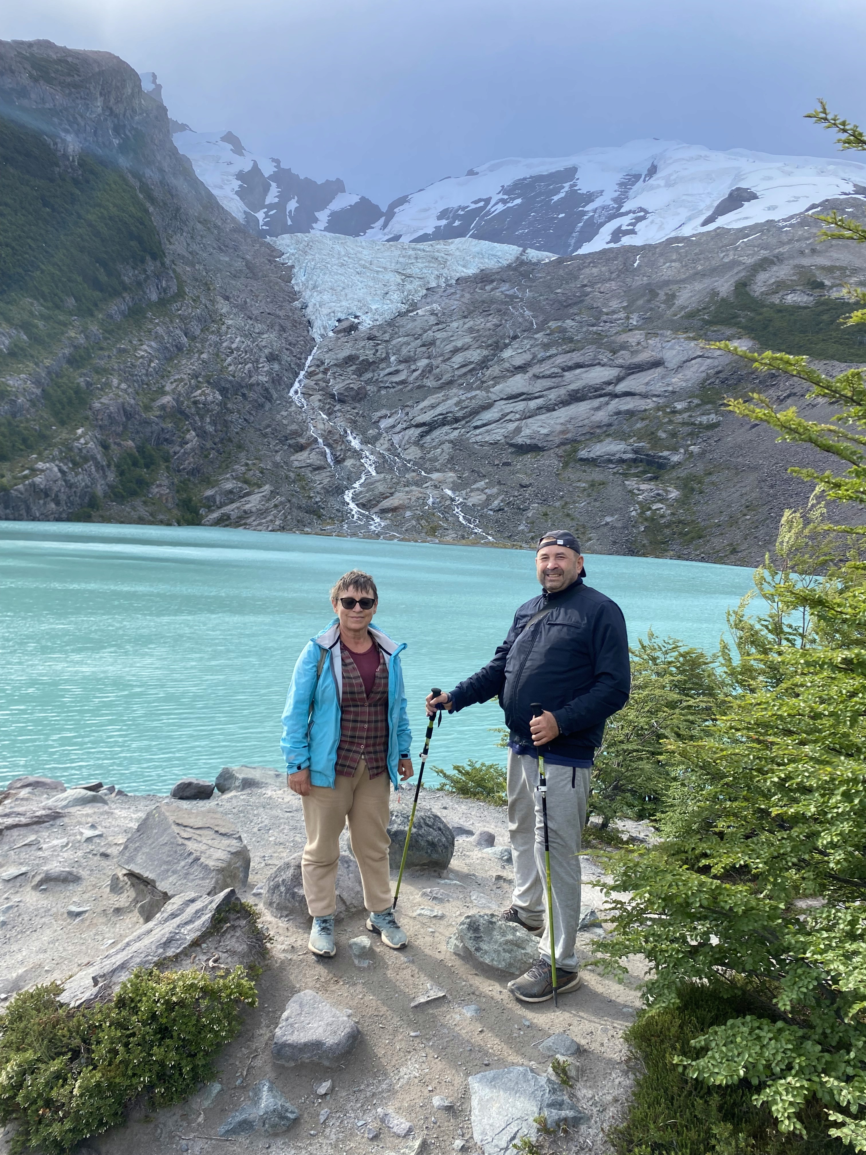 Mujer sentada sobre un tronco frente a una cascada doble en un bosque frondoso de Argentina.