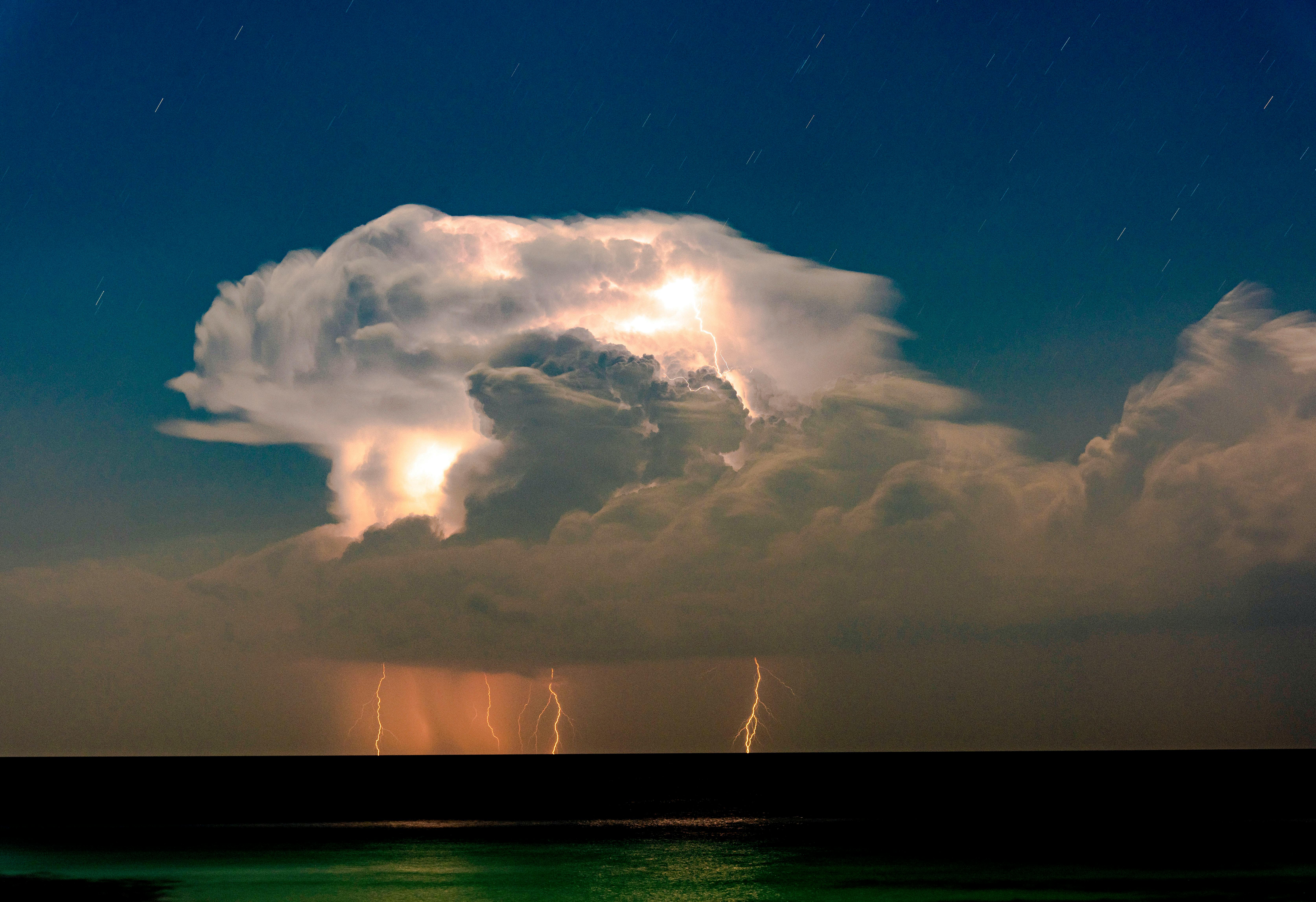 Lightning storm illuminating clouds over dark water