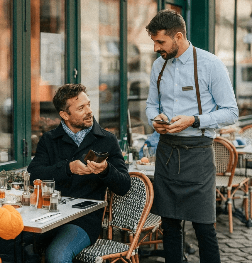 Man sitting in an outdoor restaurant, paying for food 