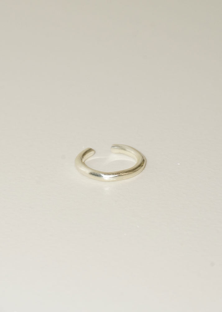 Silver open ring on a light beige background