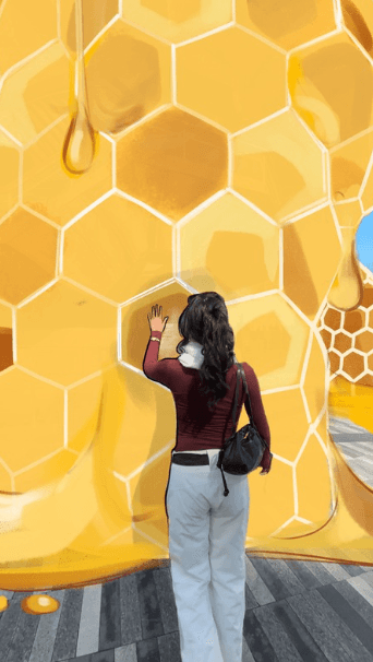 The woman reaches toward a specific cell in the honeycomb as digital honey drips appear to fall
