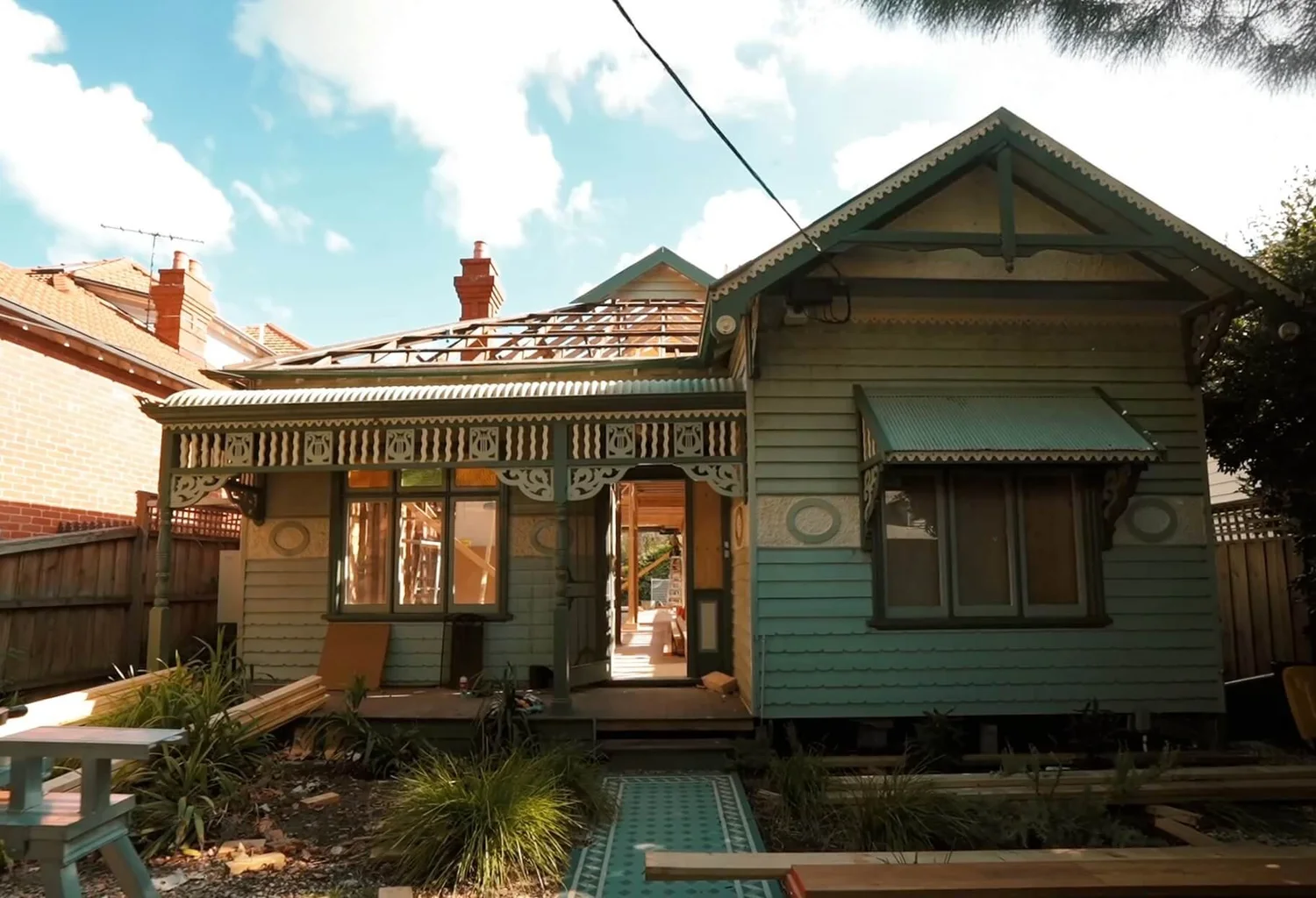 Renovation of an old Victorian house under a clear blue sky.