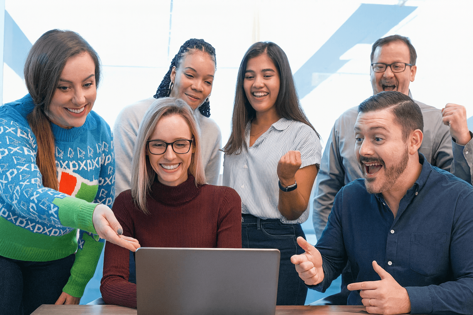 Un groupe de personnes enthousiastes rassemblées autour d'un ordinateur portable, célébrant un succès, symbolisant l'augmentation de la visibilité et des ventes grâce à Amazon.