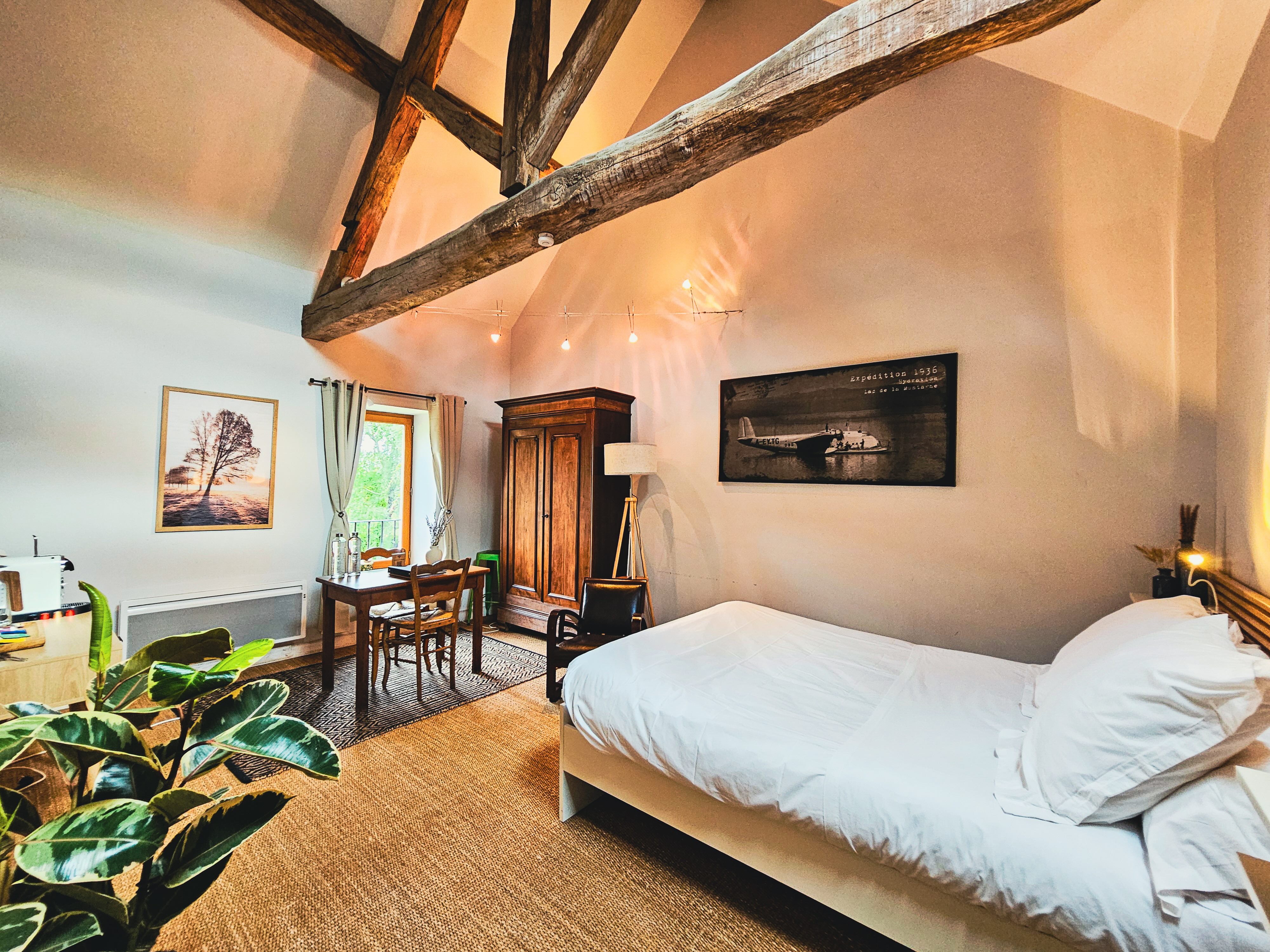 Chambre avec poutres apparentes et lit.