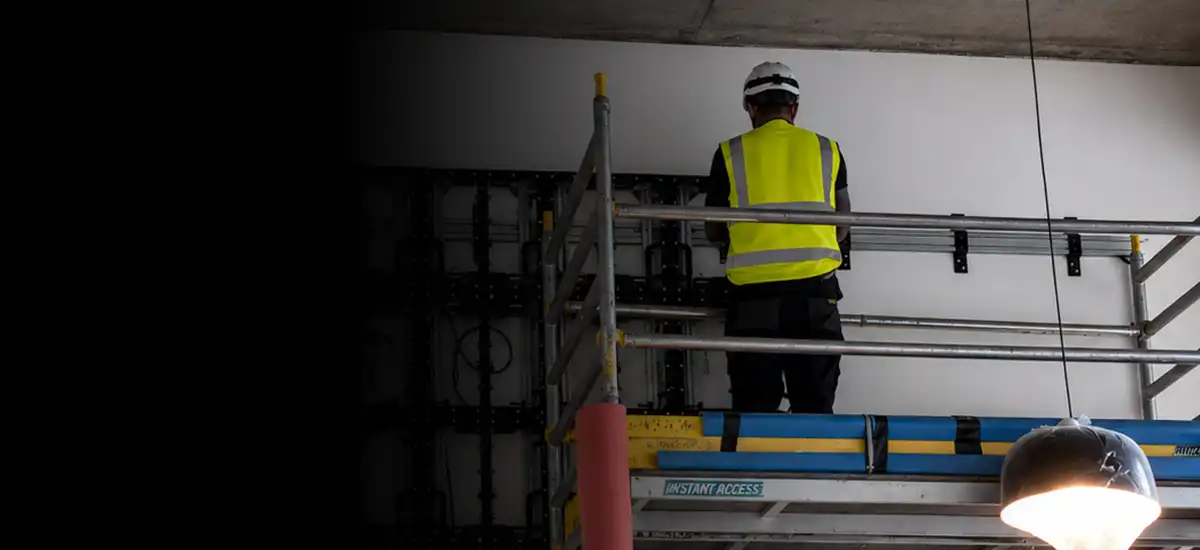 AV engineer installing a commercial display mounting system from an access platform
