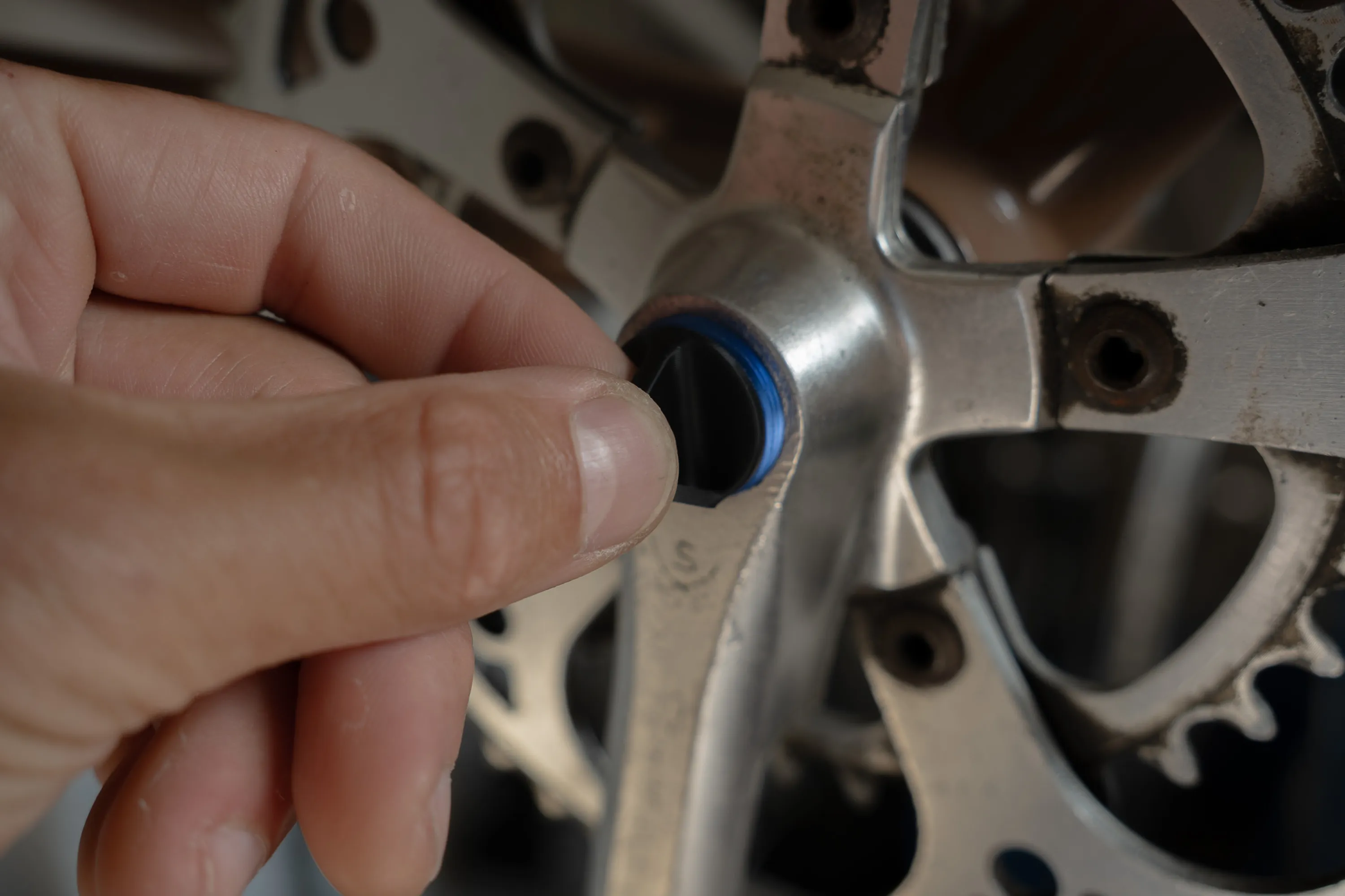 A close up of a person working on a bike crankset