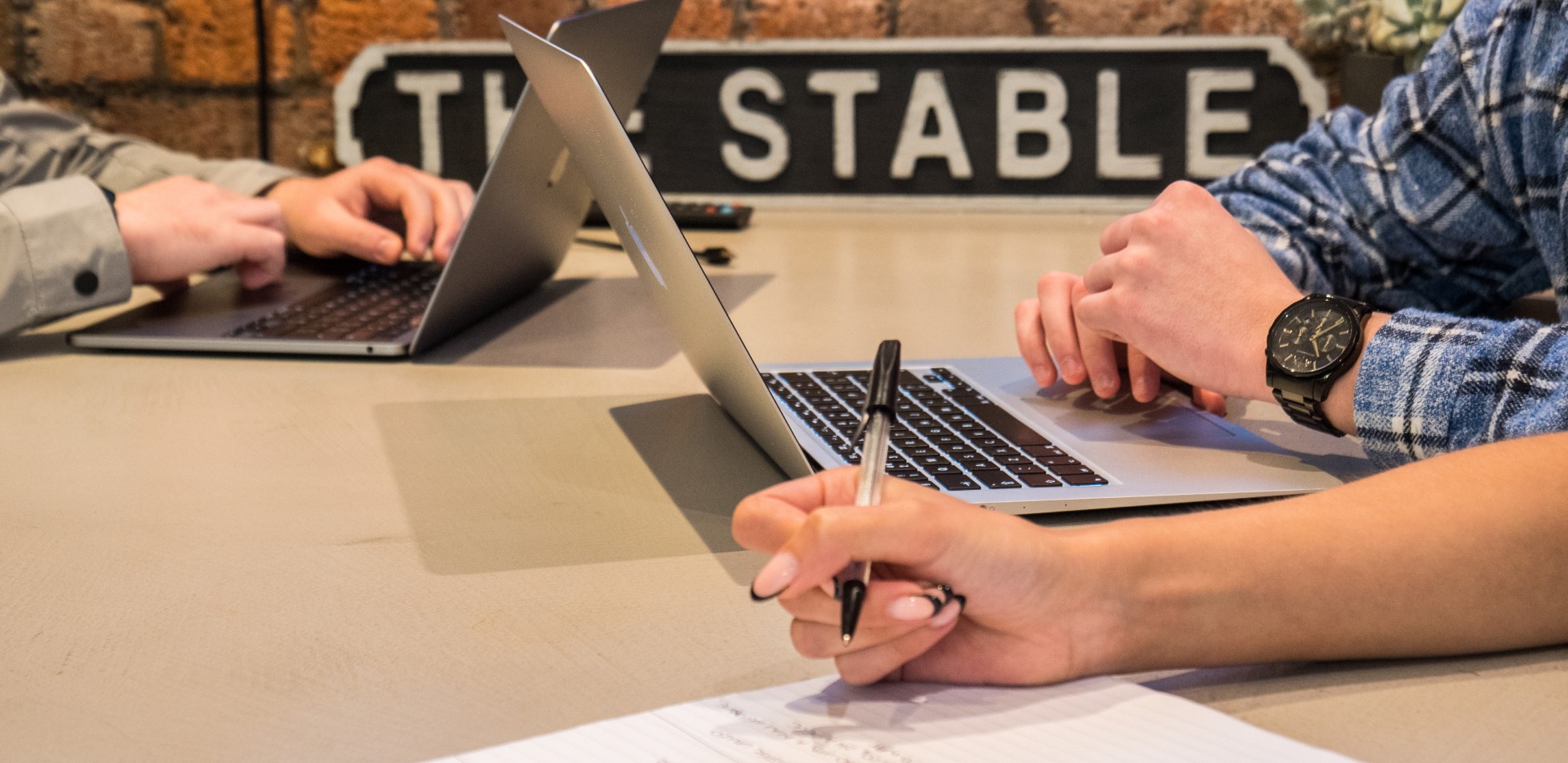 Person working on a laptop with another person's hands.