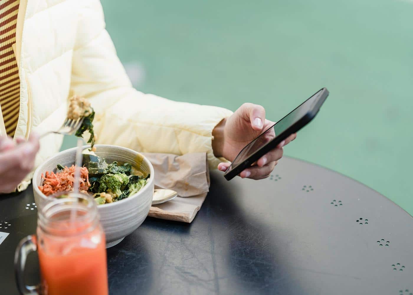 Person eating a salad while looking at smartphone