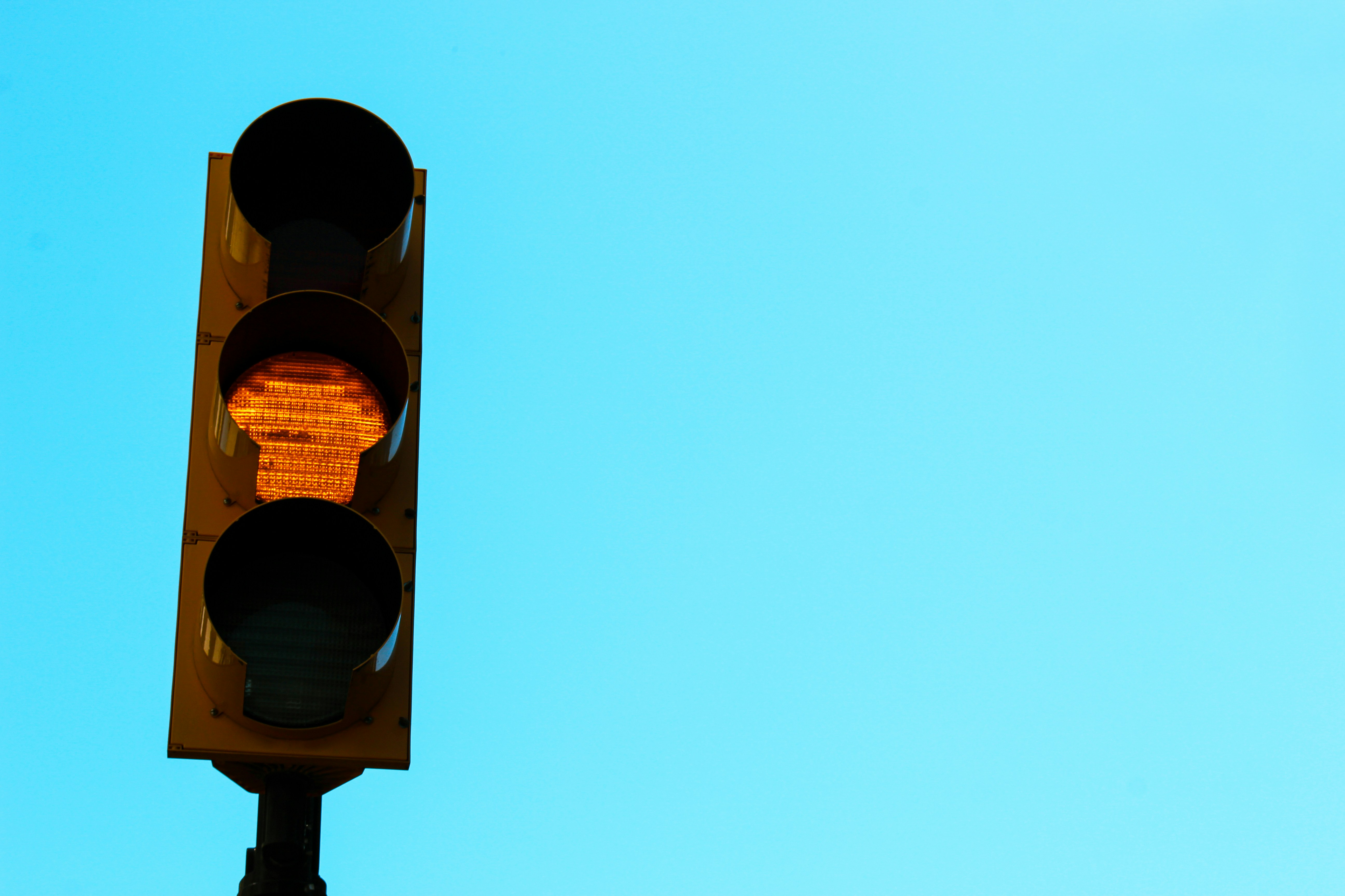 a yellow stoplight against a blue sky