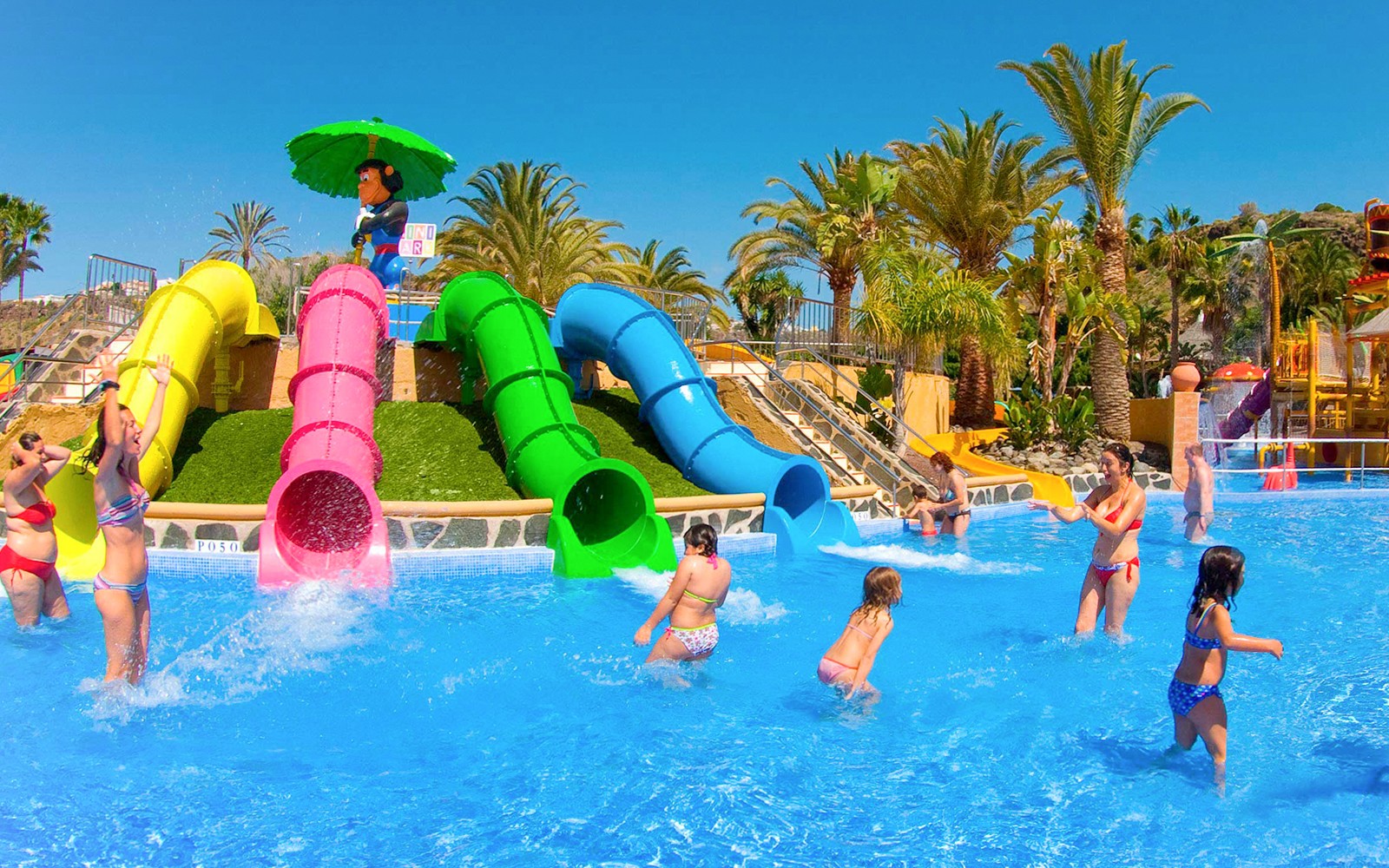Kinder spielen in der Nähe von bunten Wasserrutschen im Aqualand Maspalomas.