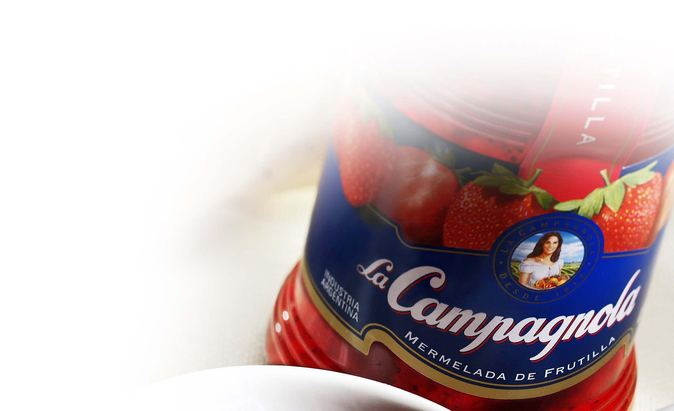 Jar of La Campagnola strawberry jam with bright red strawberries on the label. It conveys a fresh and appetizing tone, partially blurred edges.