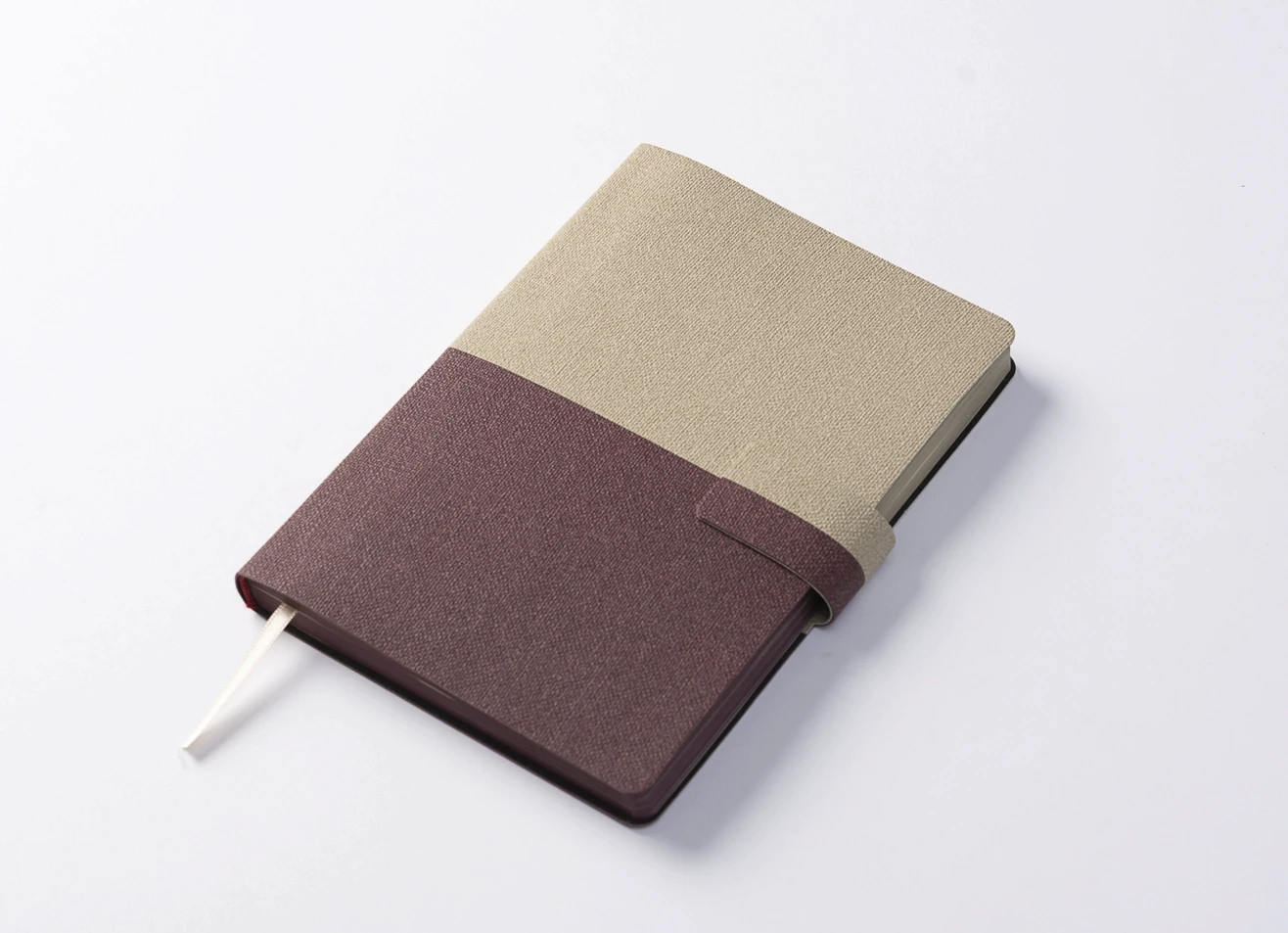 Angled view of two-tone notebook with ribbon bookmark.