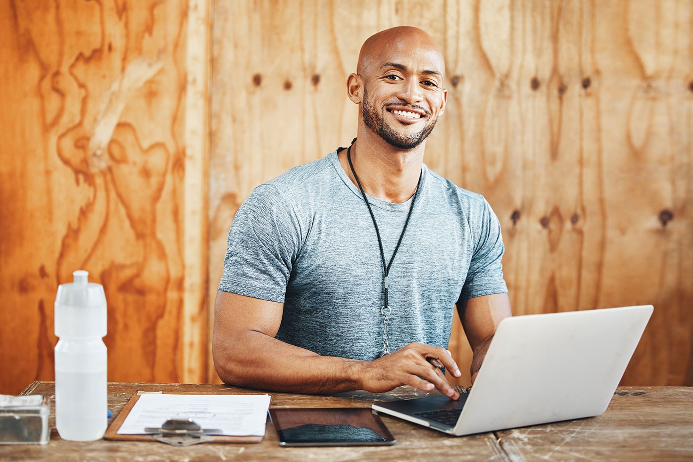 Laptop, portrait and coach with man in gym for fitness instructor, planning and digital membership record. Online schedule, personal trainer and equipment manager with person in health facility