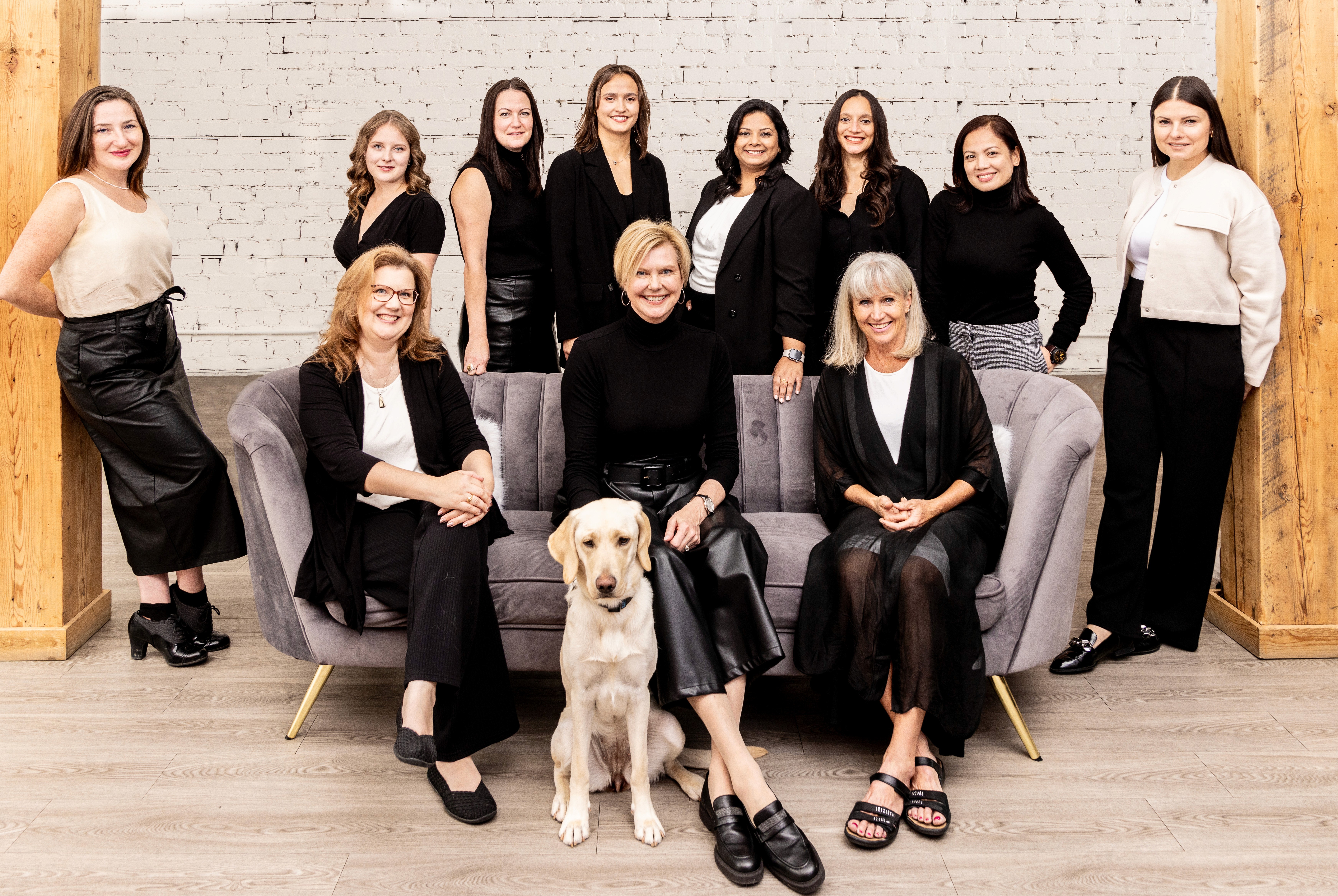 Image of Women in a design-build firm posing with a dog on a gray sofa in modern interior.