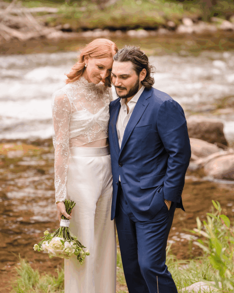 Newlyweds standing together beside a rocky river