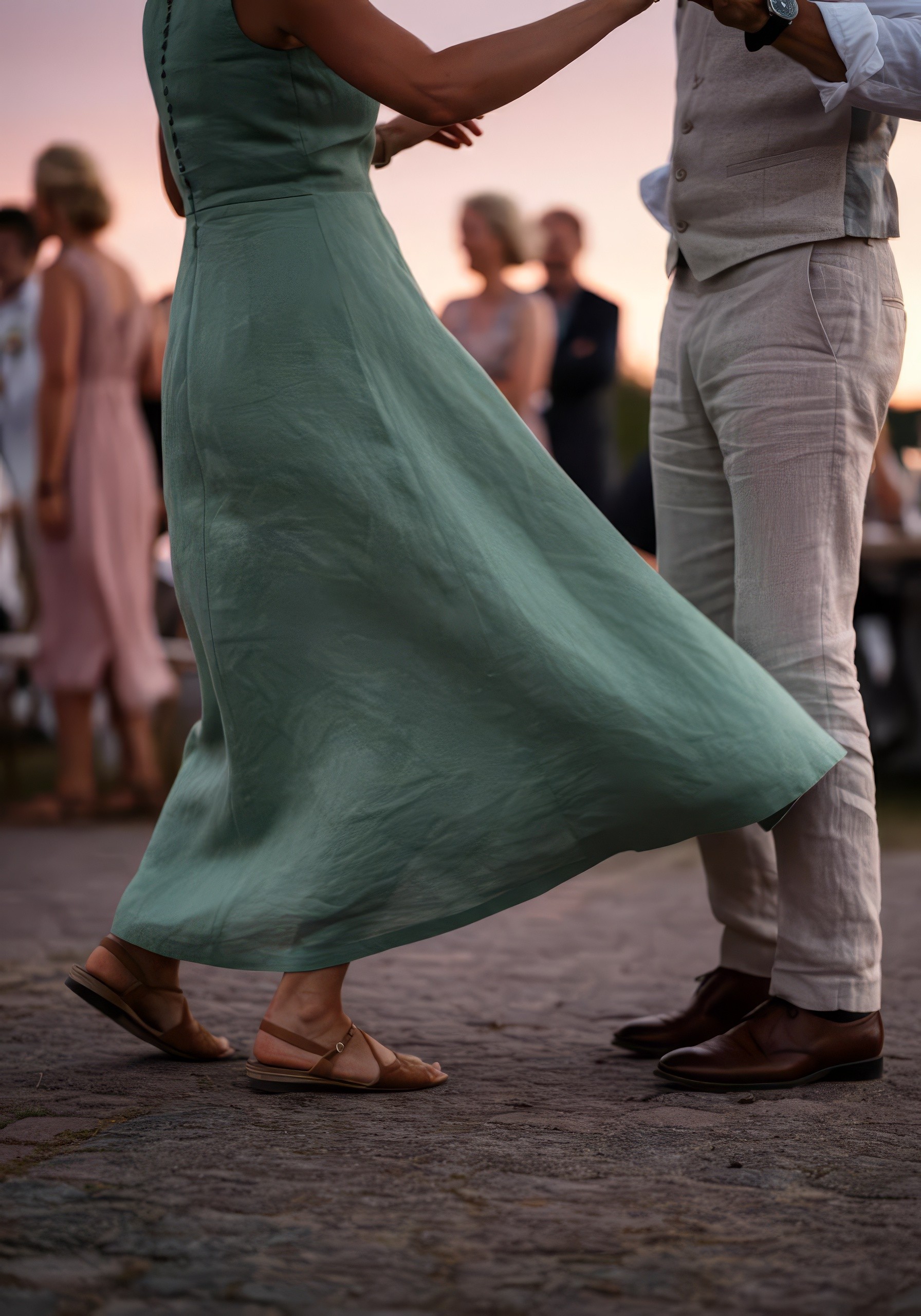 A couple dances closely, showcasing a flowing green dress, against a soft, blurred background of other guests.