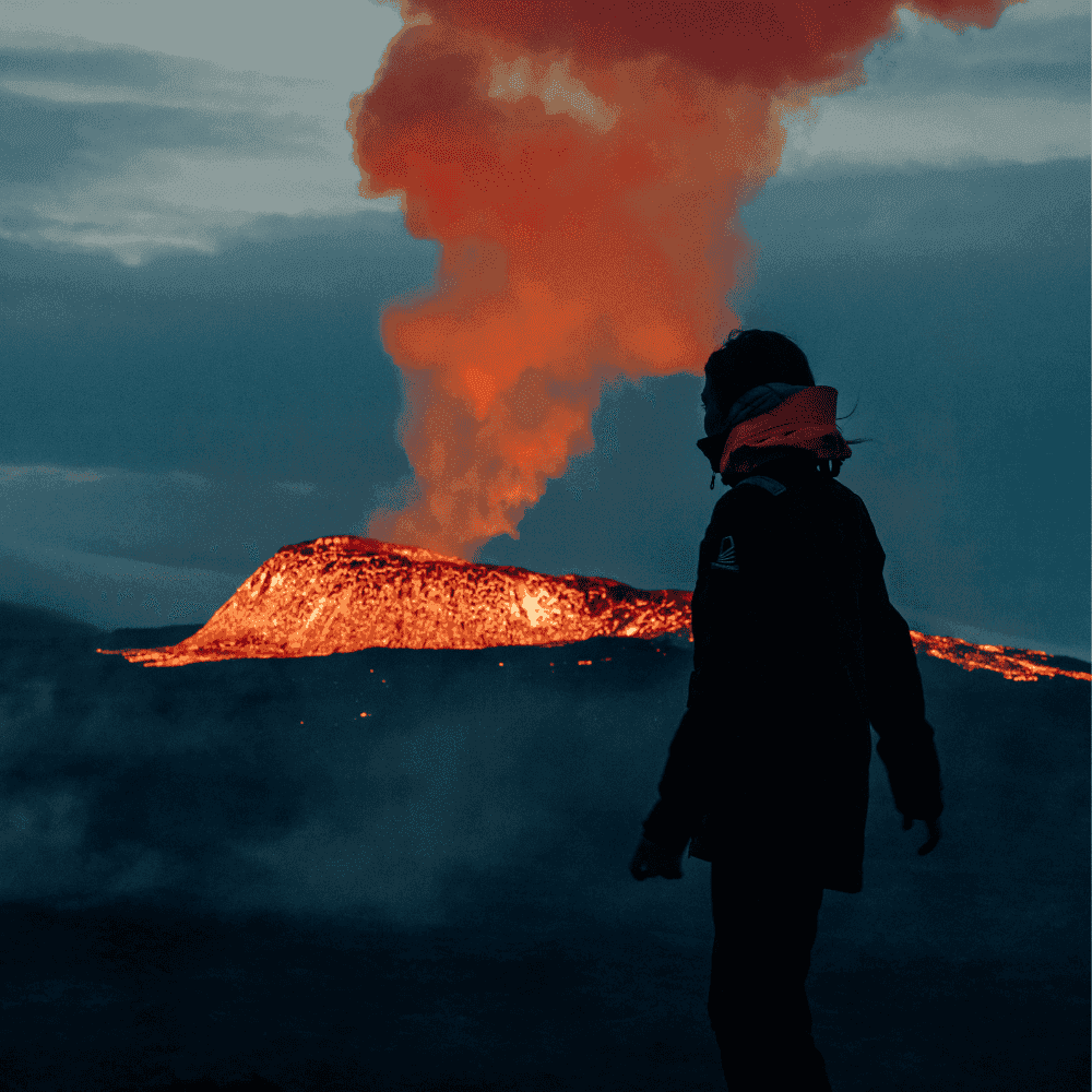 Fagradalsfjall volcanic eruption in Iceland with glowing lava and smoke plume, person observing active lava flow on Reykjanes Peninsula