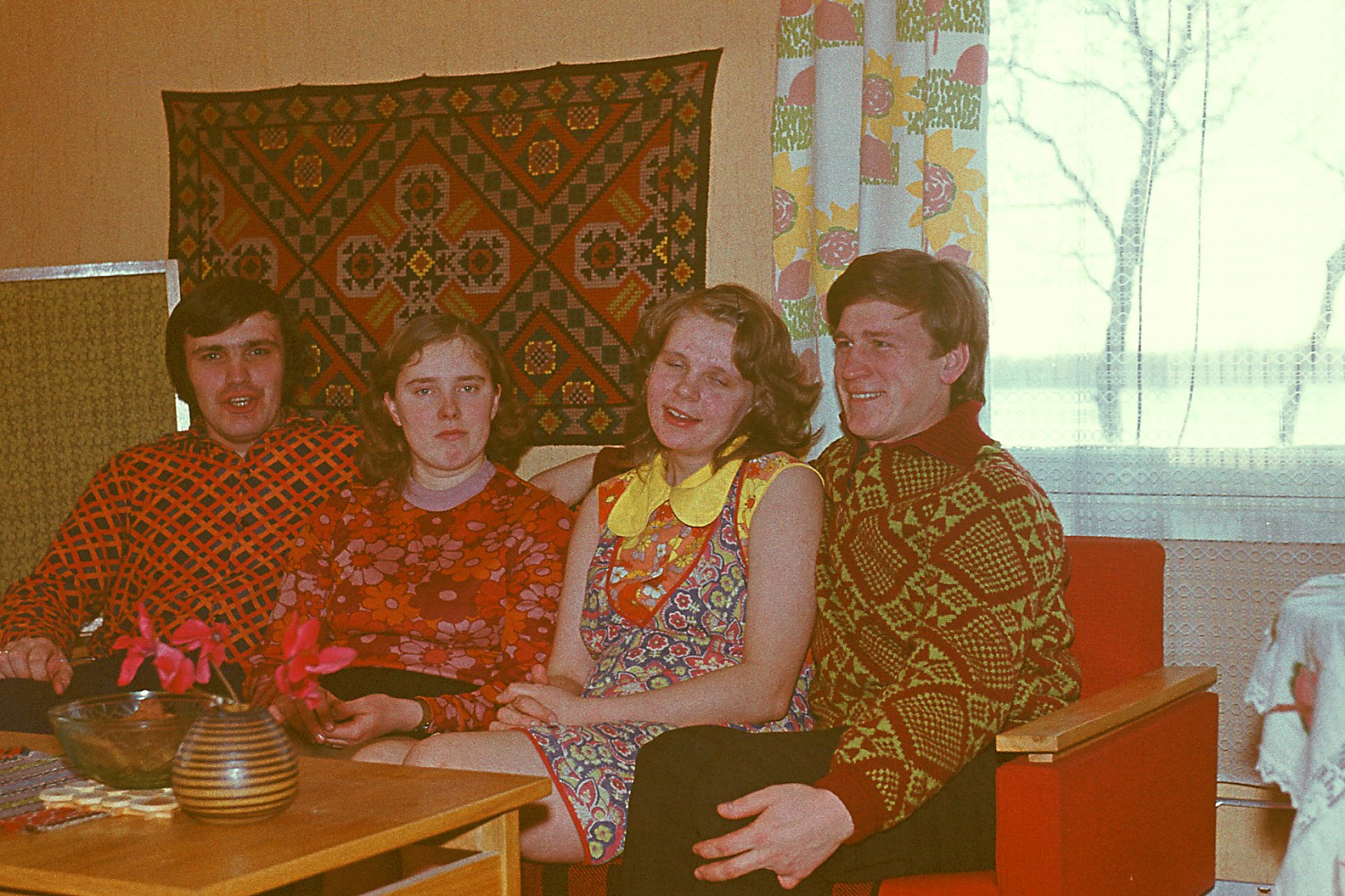 Neli noort inimest diivanil mustriliste riietega