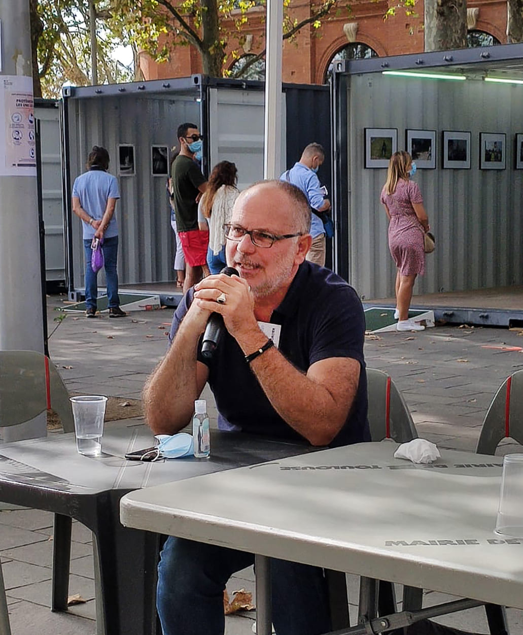 Frédéric Bourcier parlant au micro lors d’une rencontre autour de son exposition photo installée dans des conteneurs urbains.