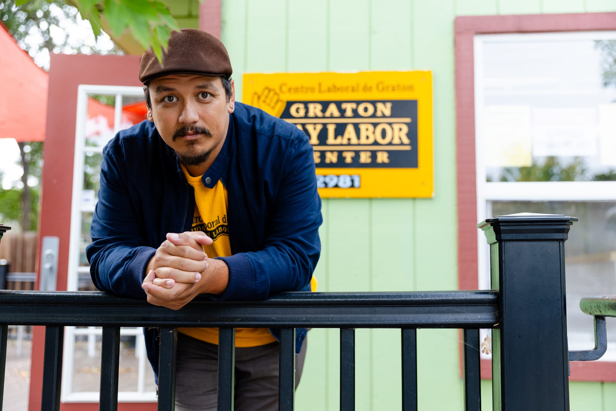 a young Latino man looks into the camera while leaning over a black bannister