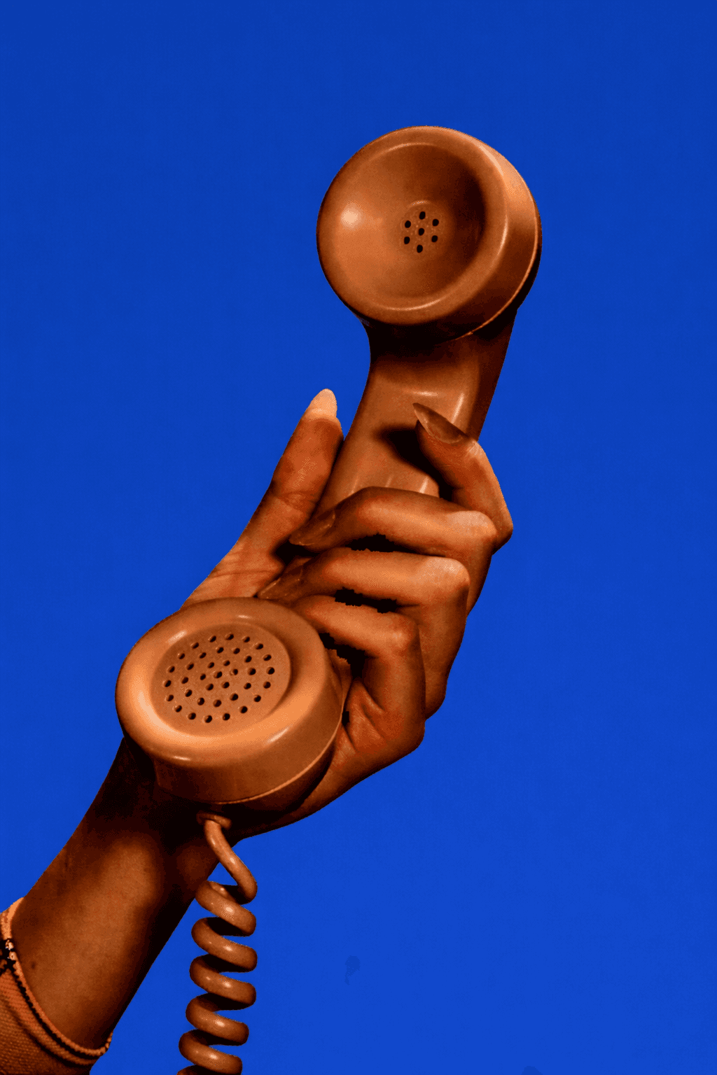 Man in a suit talking on the phone while gesturing at a desk