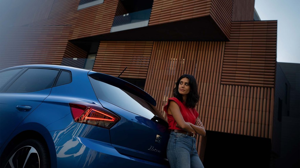 "Un SUV Citroën azul circulando por una calle urbana con fachadas de tiendas y edificios antiguos en un entorno soleado."