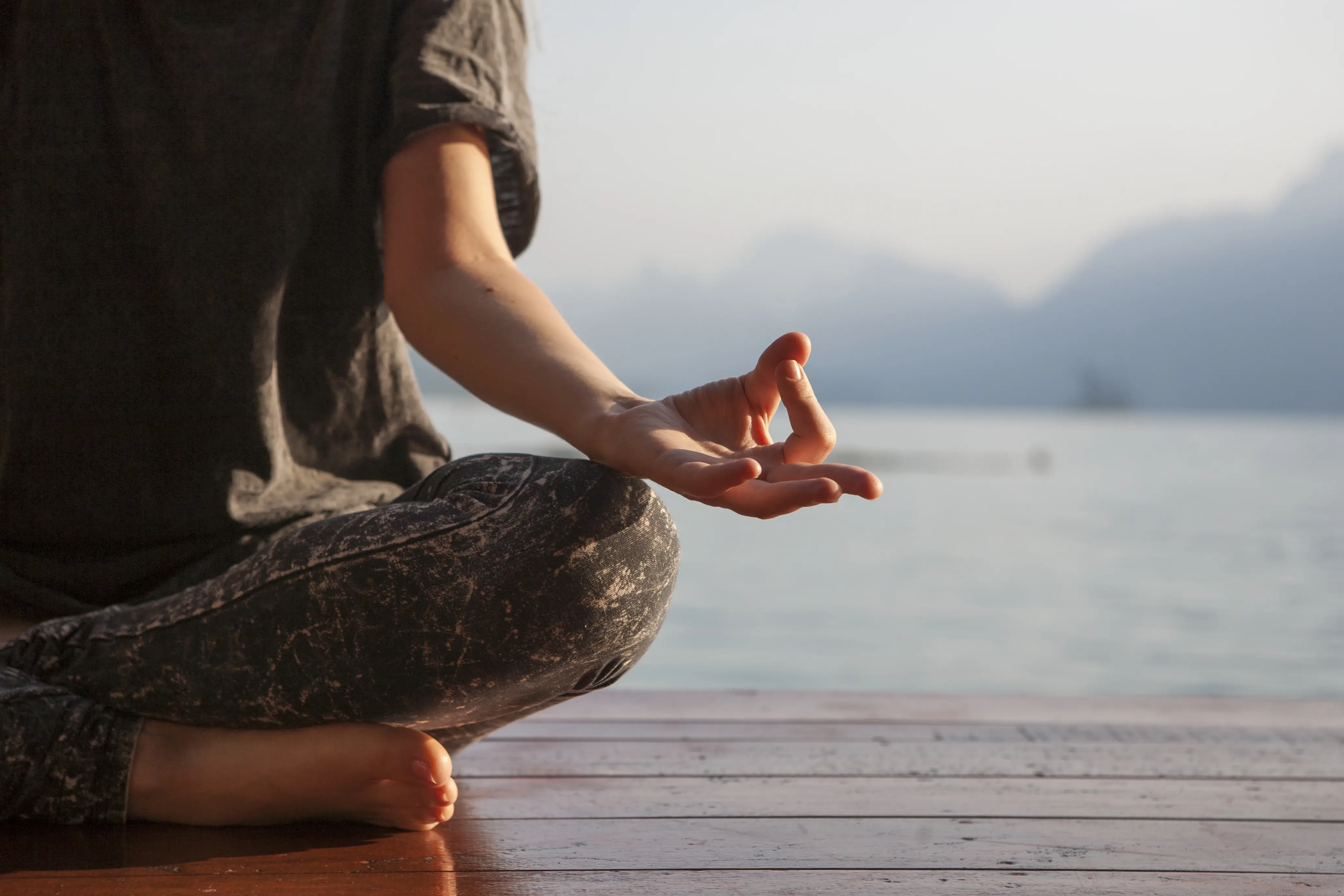Persona meditando al aire libre frente a un lago, representando rutinas mentales saludables y pequeños gestos diarios.