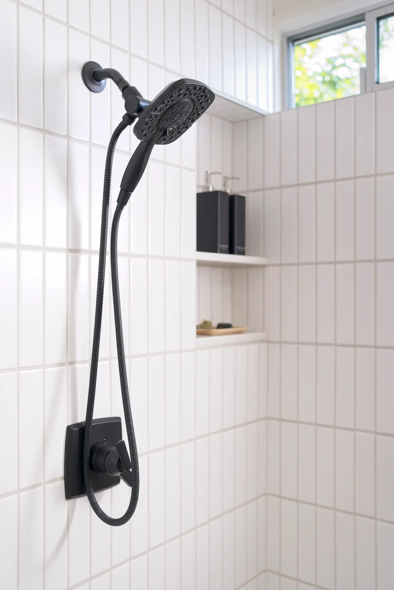 Close-up view of the shower enclosure, focusing on the shower head and tile work in the primary bathroom of the Fairhaven Eichler Tract remodel. Photo by Todd Huge.
