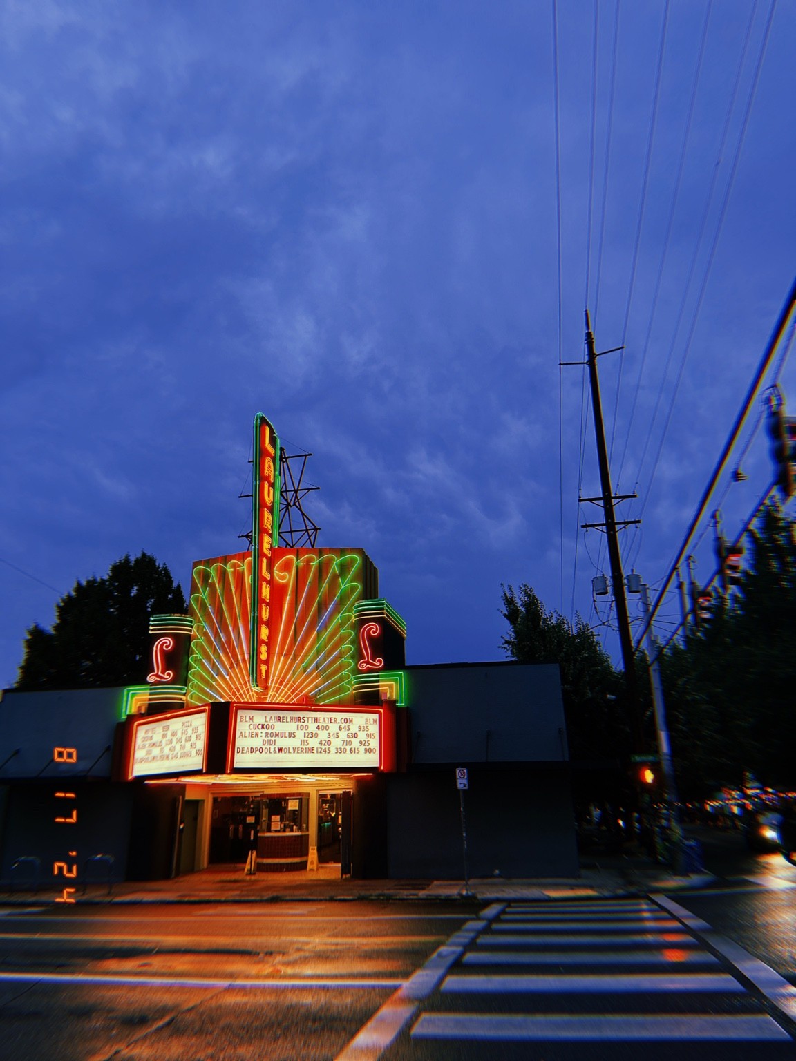 Laurelhurst Theater neon marquee beneath a blue evening sky, with a striped pedestrian crossing