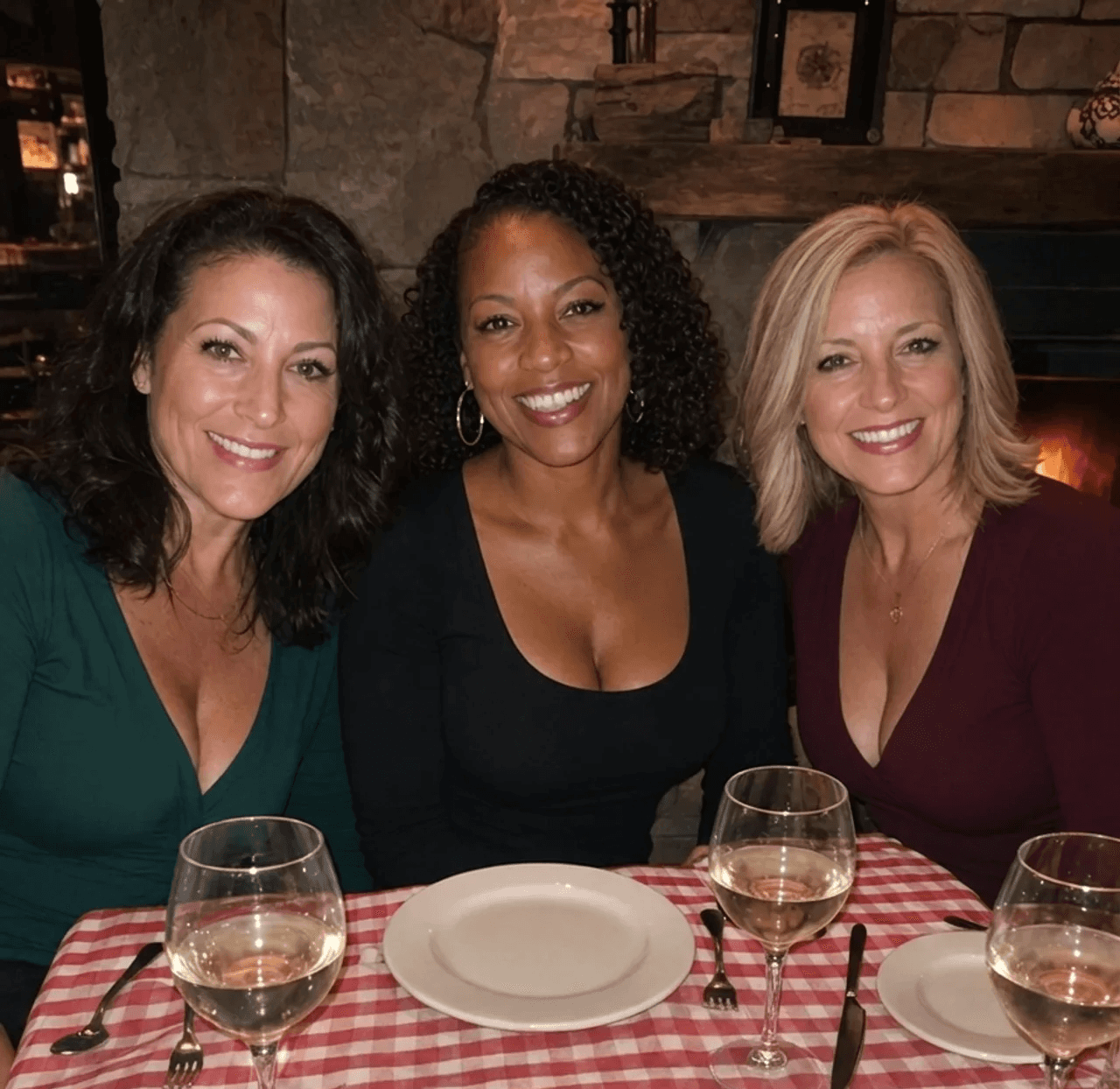 Candid dinner, women 50+ laughing, one empty chair