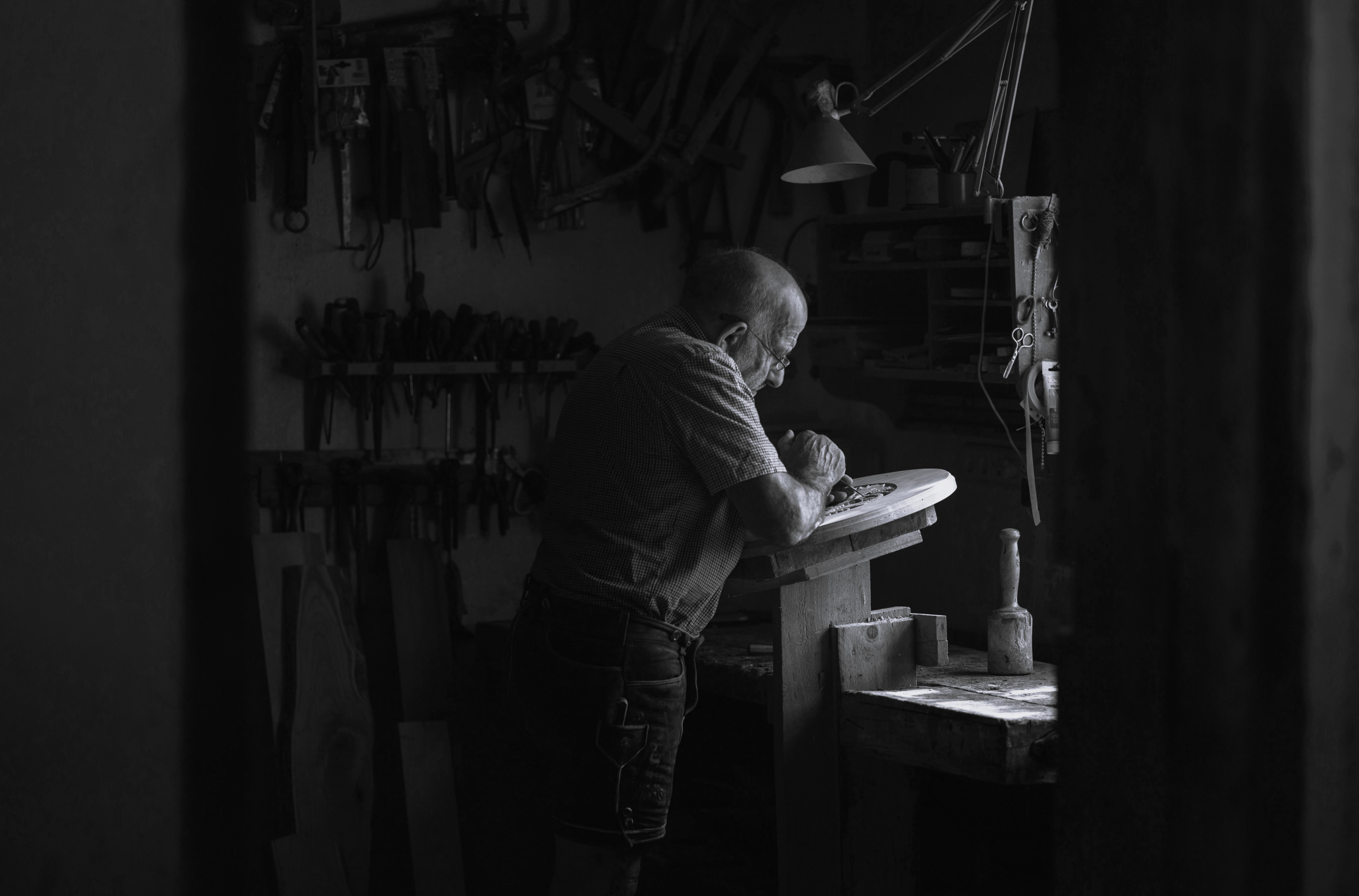 Black and white photo showing a man working with wooden furniture.