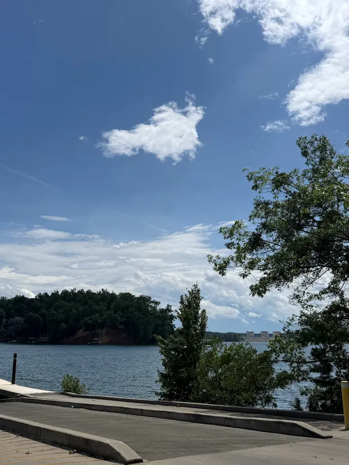 Boat ramp at Lake Keowee surrounded by trees with blue sky, clouds, and a quiet lakeside setting.