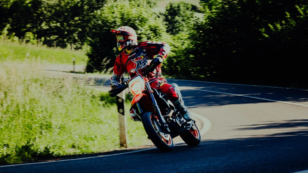 Motorcyclist leaning into a curve in a green outdoor setting