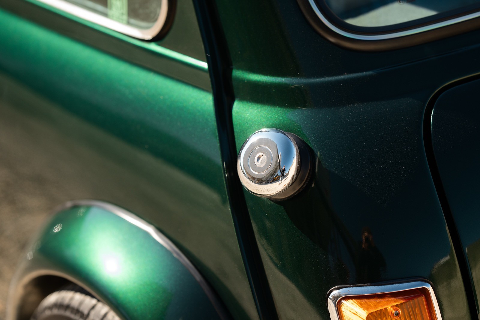 A small, green and black vehicle parked on a sandy surface, with a warm sunset lighting the scene.