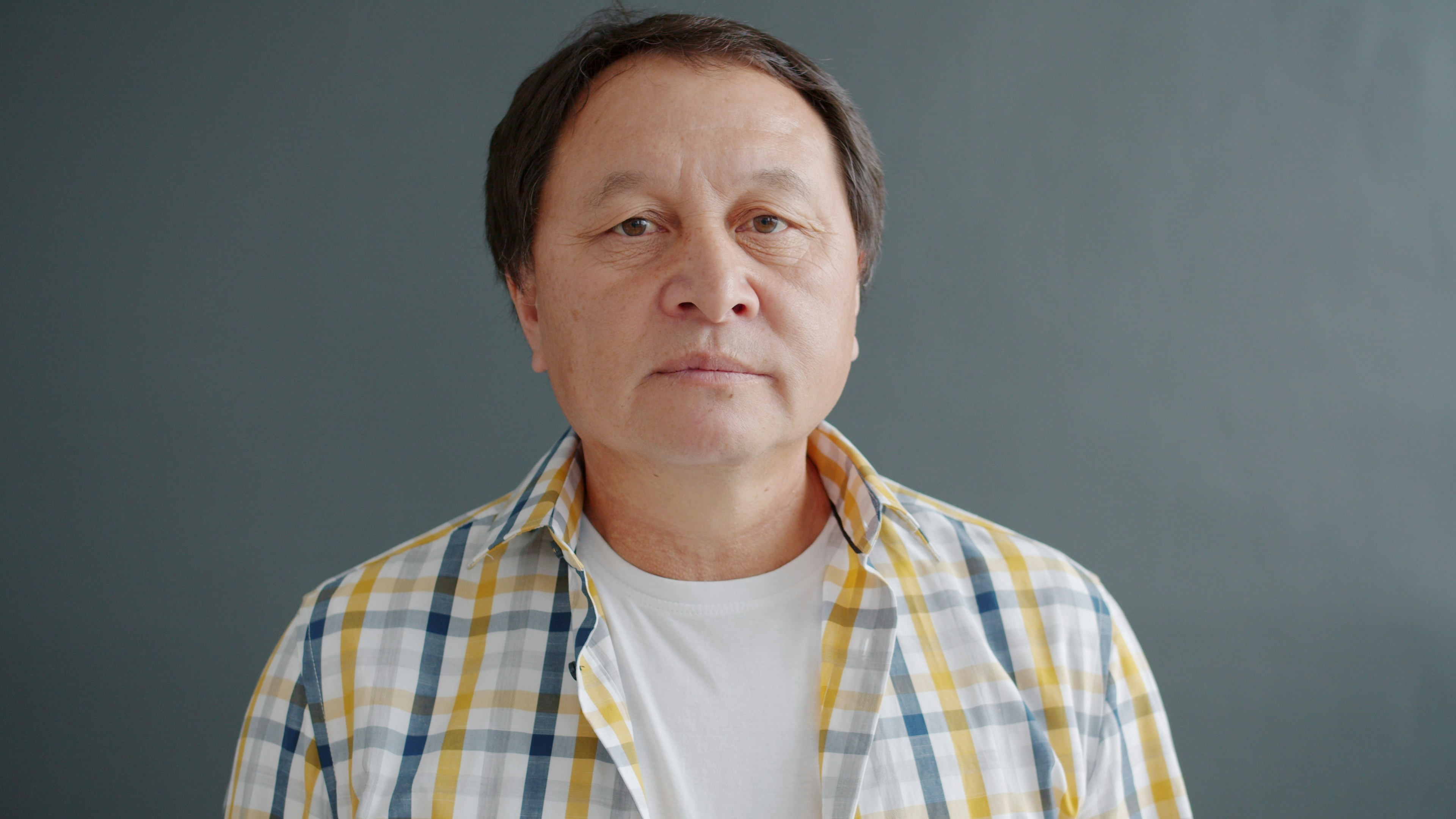 An older asian man in a plaid shirt