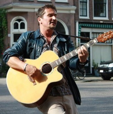 A musician playing an acoustic guitar on the street