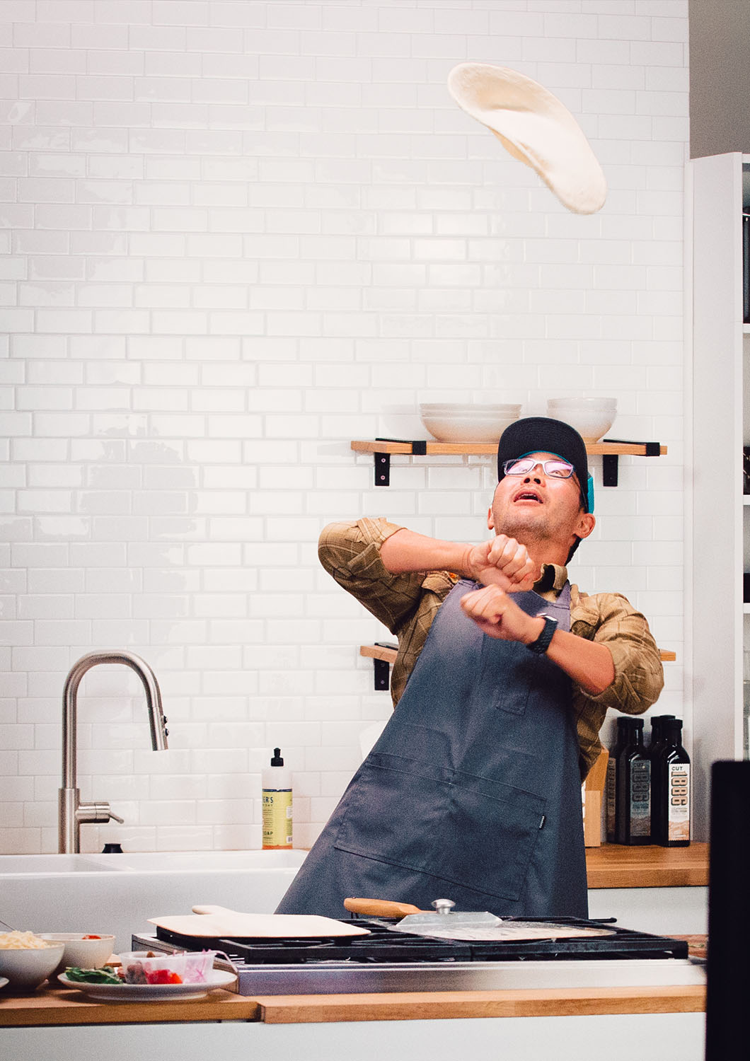 Manny Chao of Georgetown Brewing throws a pizza crust in the air while making fresh pizza on set at the studio kitchen at Particle Studio in Seattle WA.