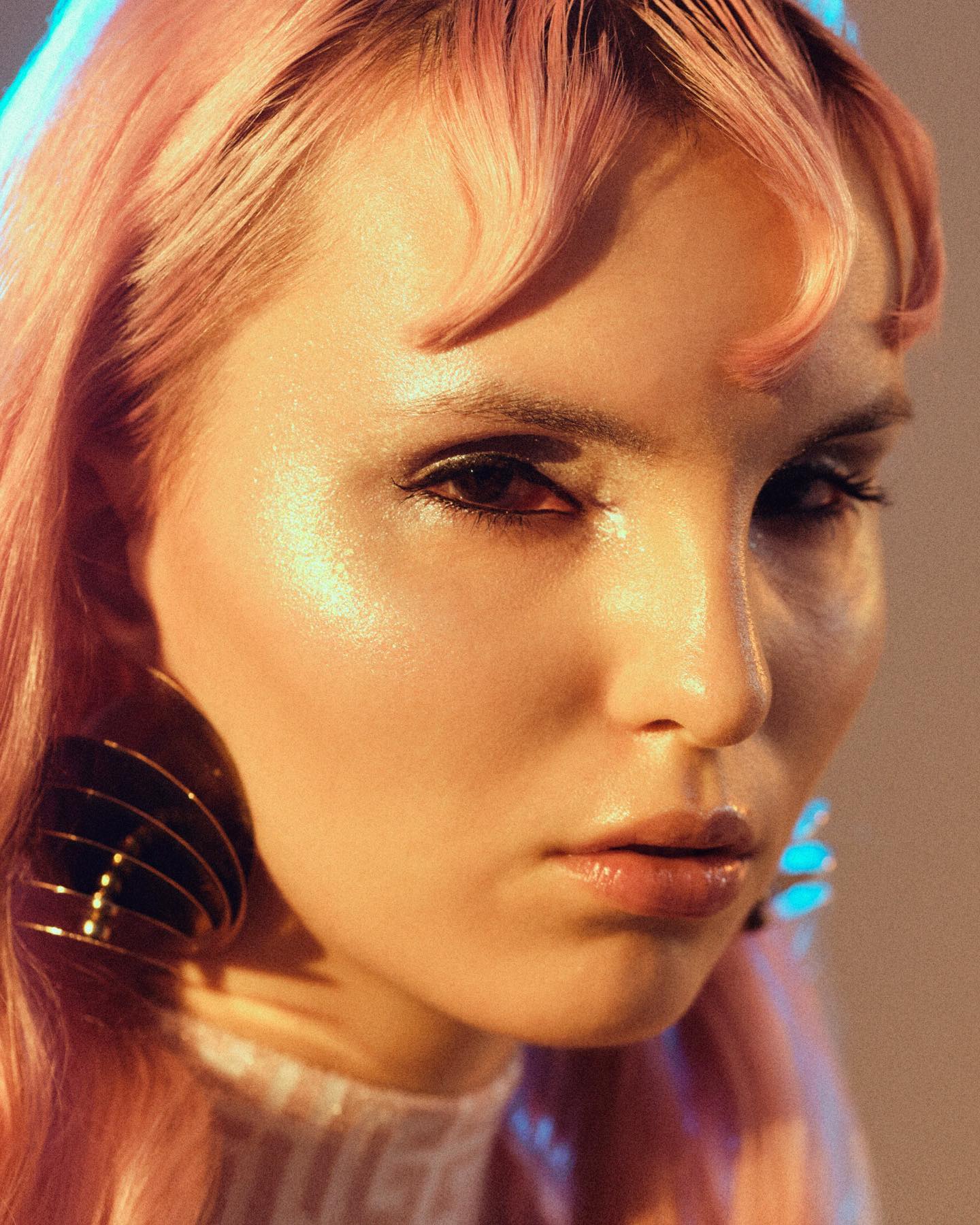 Close-up beauty portrait with warm light and defined eye makeup.