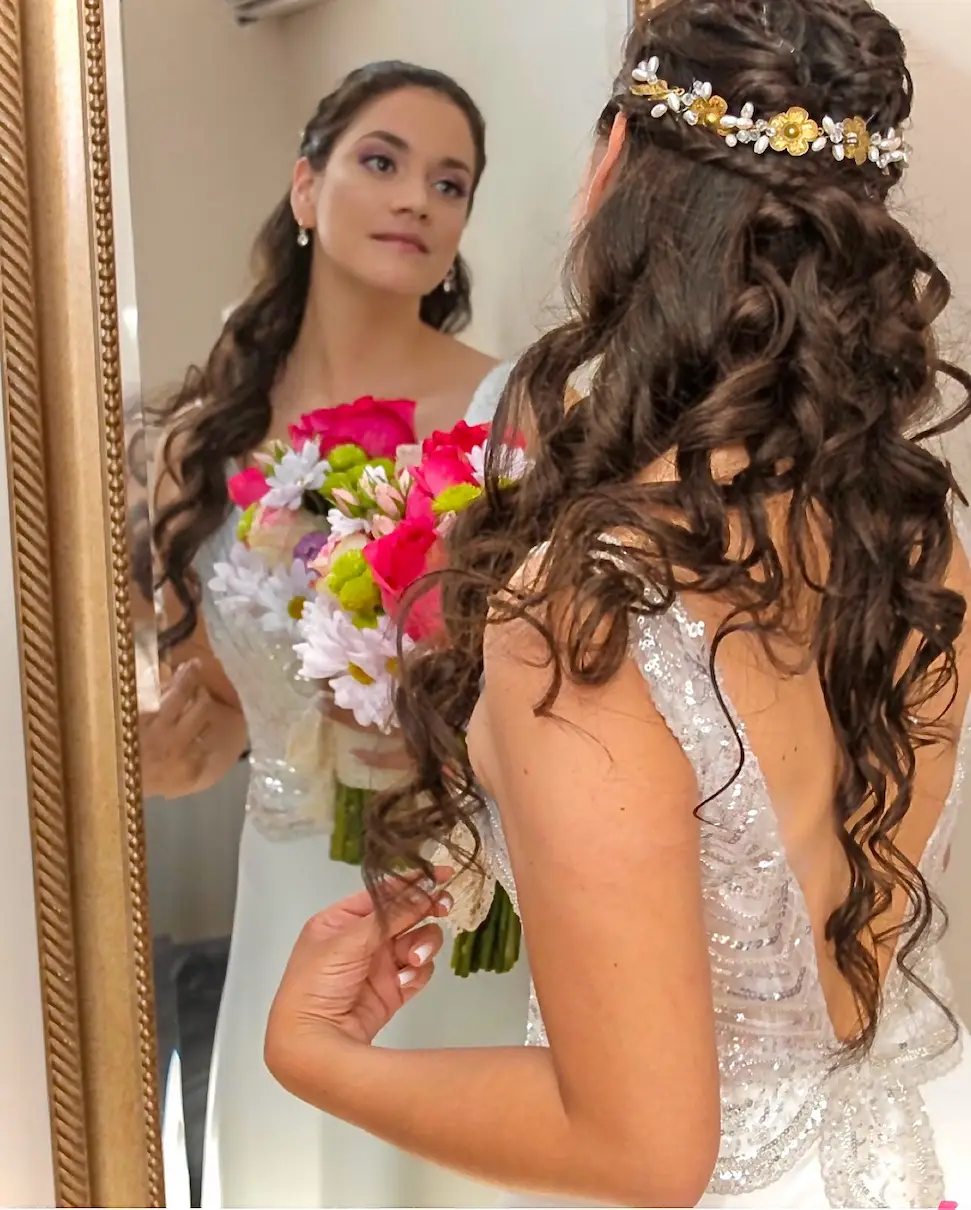 Novia con maquillaje profesional y peinado elaborado frente al espejo
