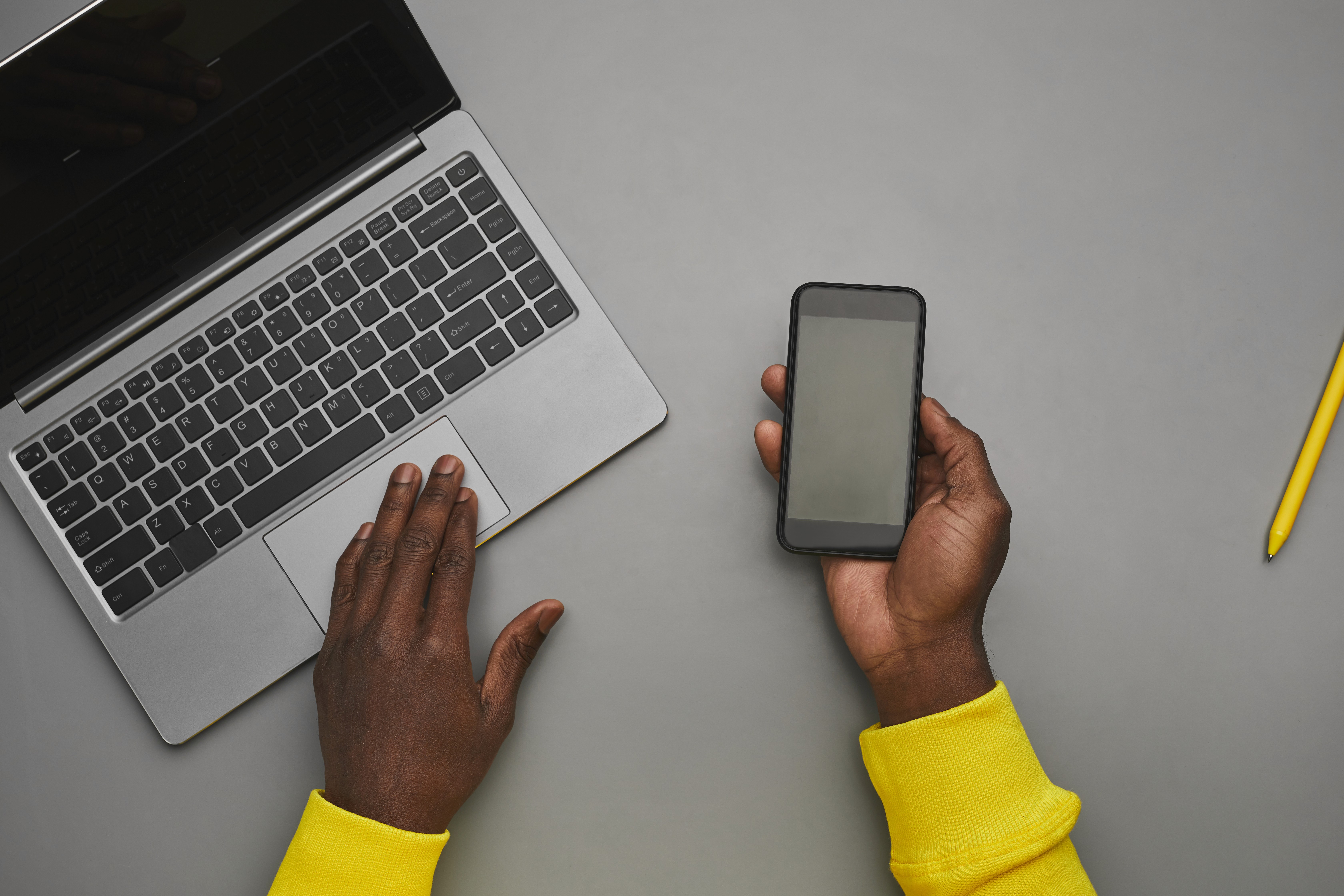 A professional using a phone beside a laptop at their desk