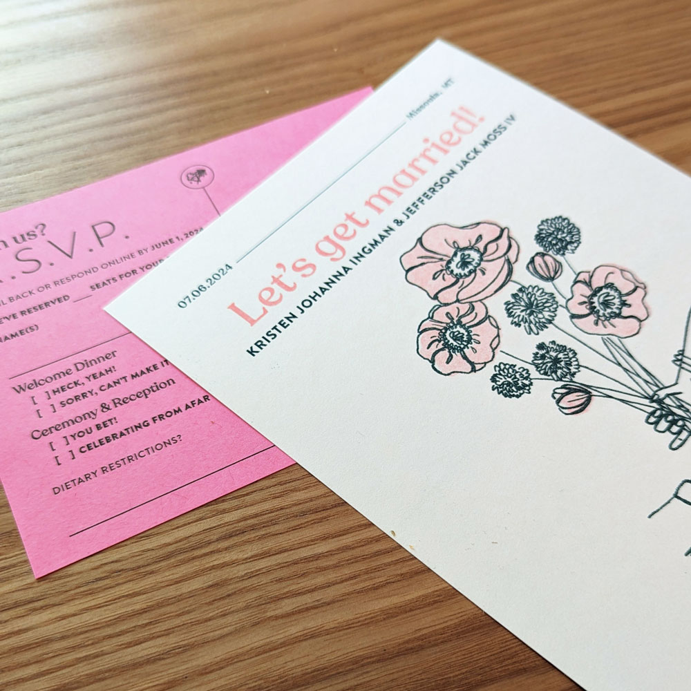 Close-up of wedding invite and save the date featuring pink poppies