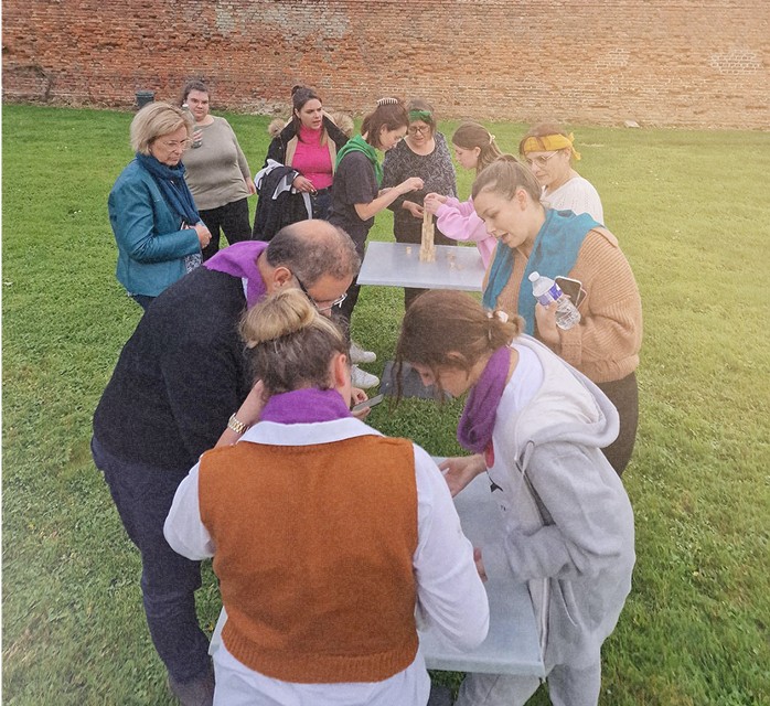 Groupe de personnes en extérieur qui manipule des objets tandis que d'autres observent ou se préparent à agir.