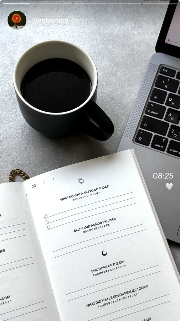 BETTER JOURNEY journal page with daily prompts next to a coffee mug and laptop, illustrating its integration into daily work and reflection routines